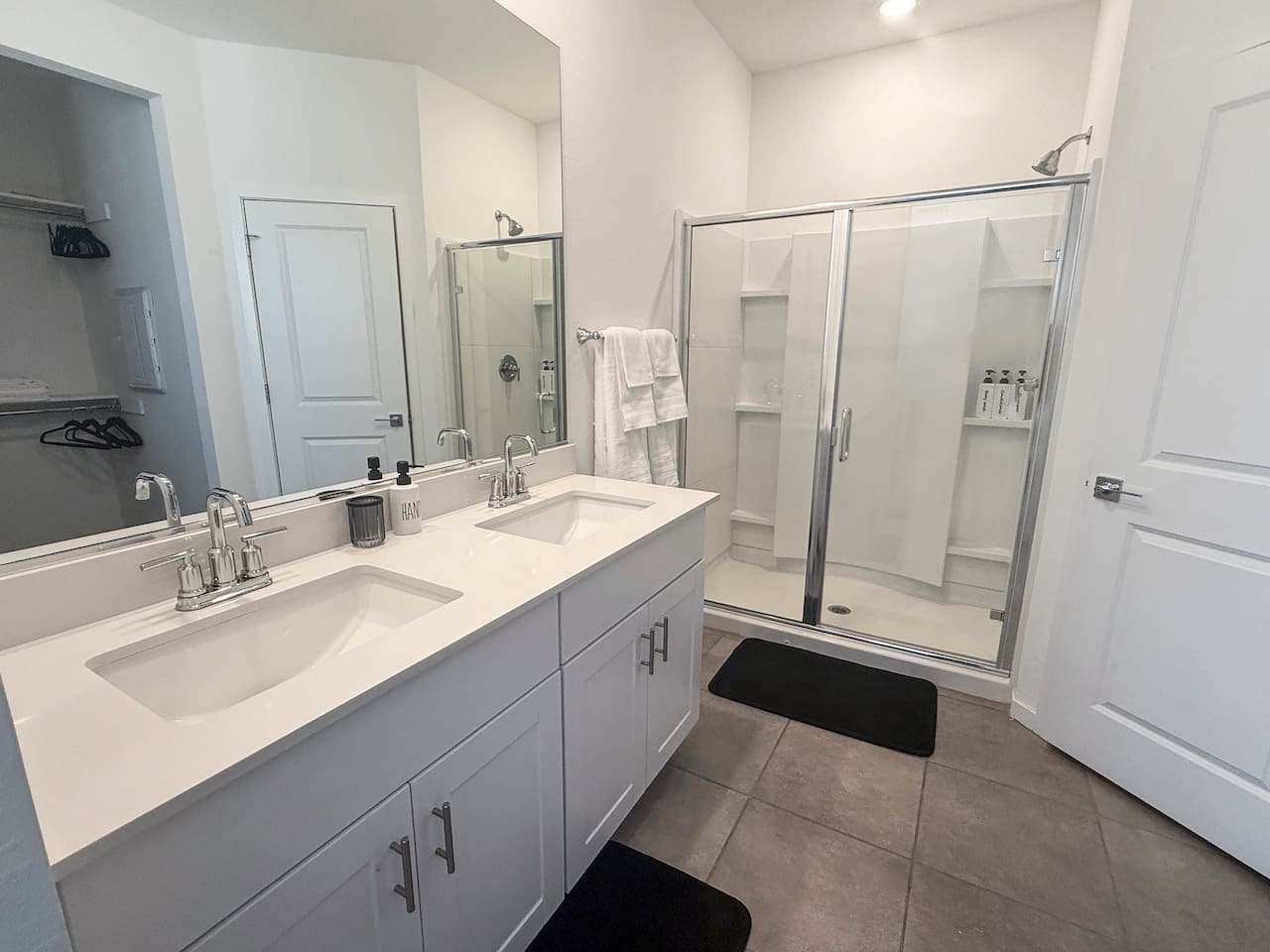 Bathroom with double vanity, mirror, and glass shower