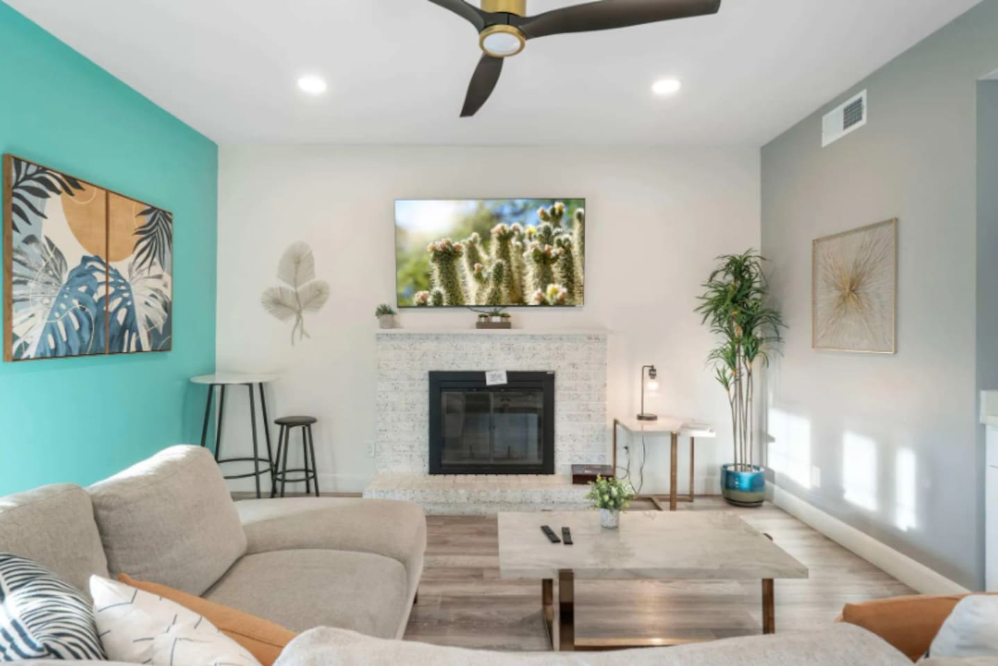 Modern living room with fireplace, smart TV, turquoise accent wall, and plenty of natural light.