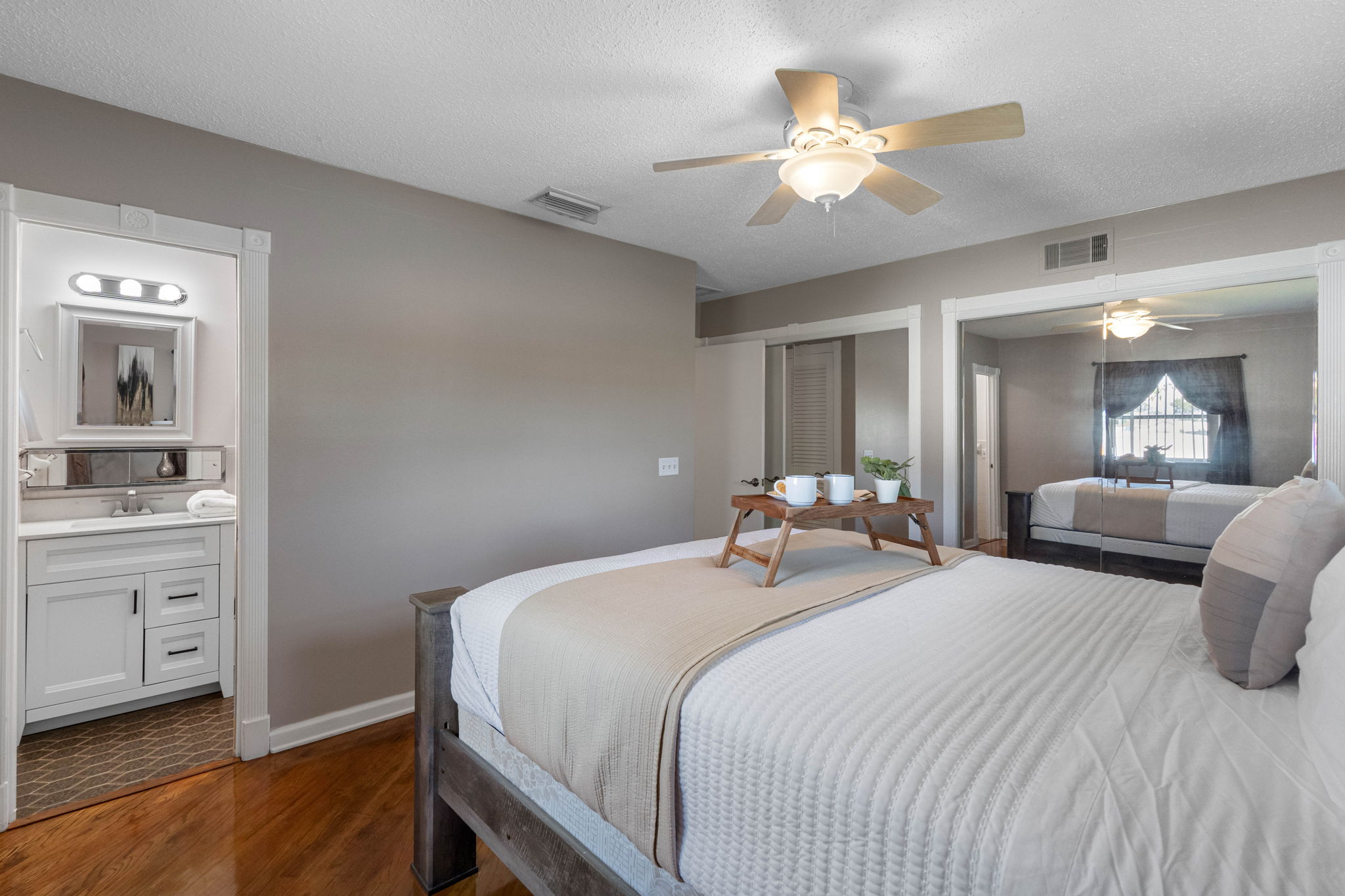 This bedroom offers a calming atmosphere with neutral tones, a ceiling fan, and direct access to its own ensuite bathroom.