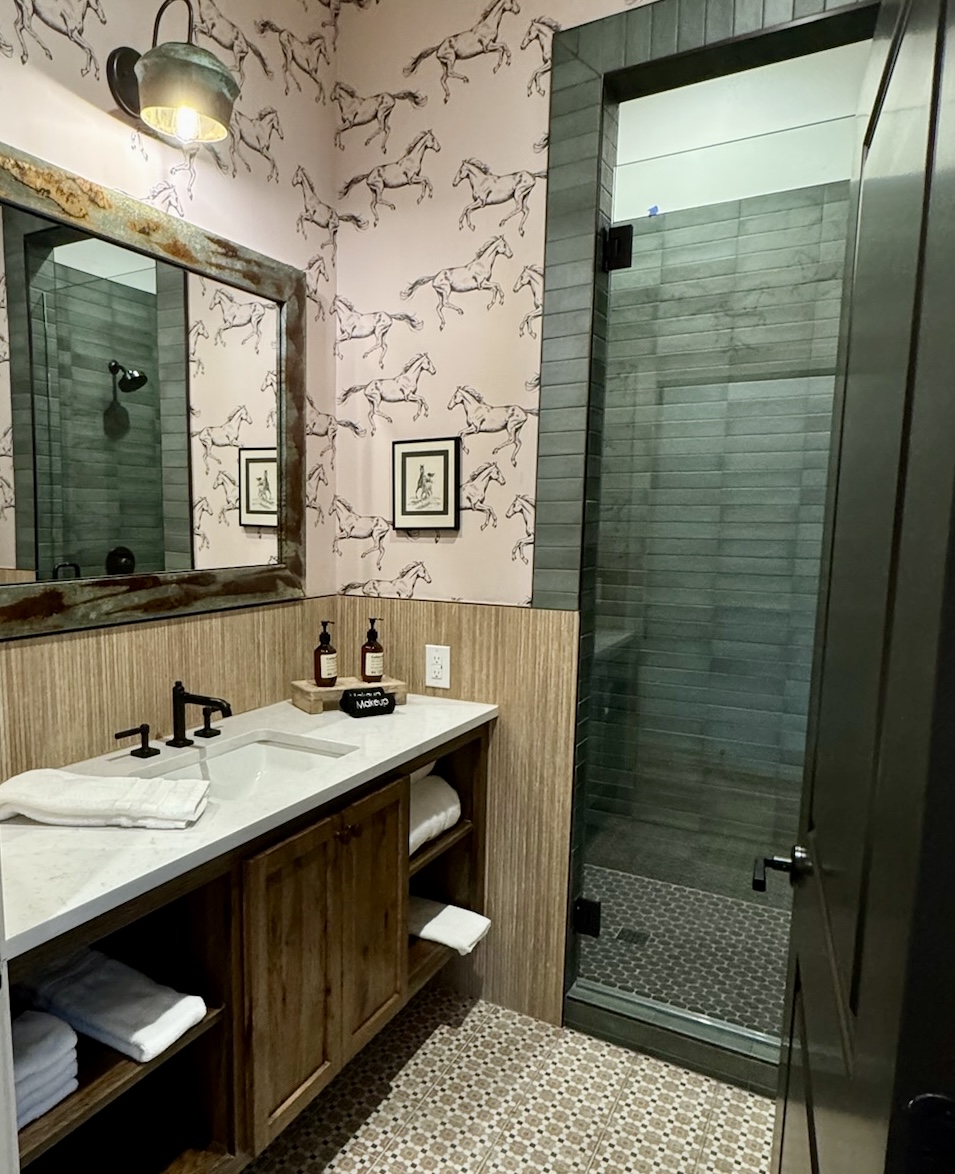  Rancher's Rest private en-suite bath — designer vanity, walk-in tile shower, modern Western finishes. Every bedroom has its own bath in your Gaines Ranch on the Square group reservation.