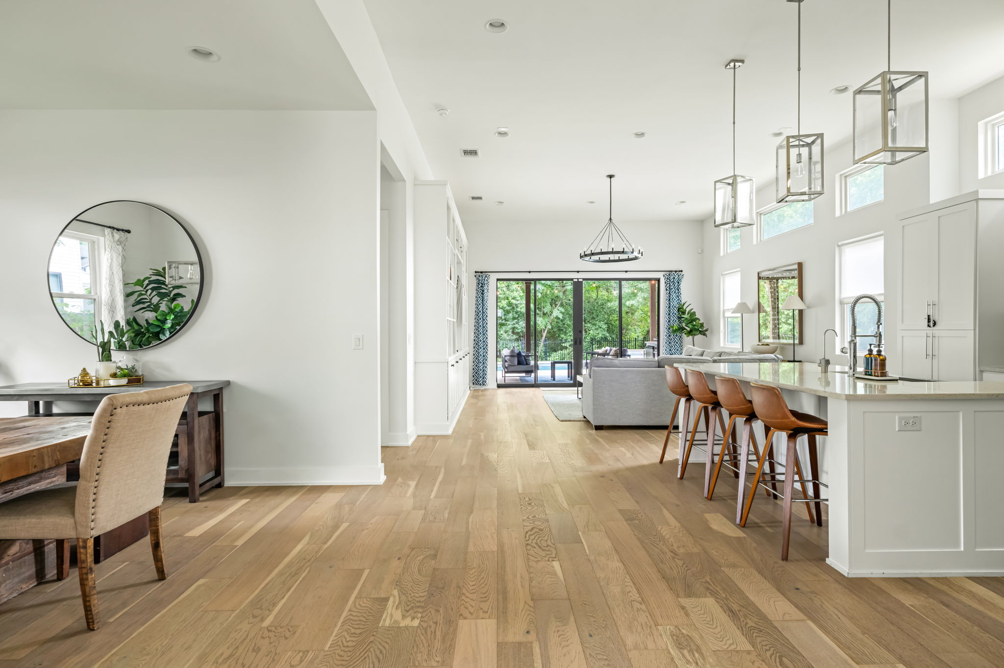 Bright, open-concept kitchen and dining area featuring a statement chandelier, round mirror accent, and seamless flow to the living space — ideal for entertaining.