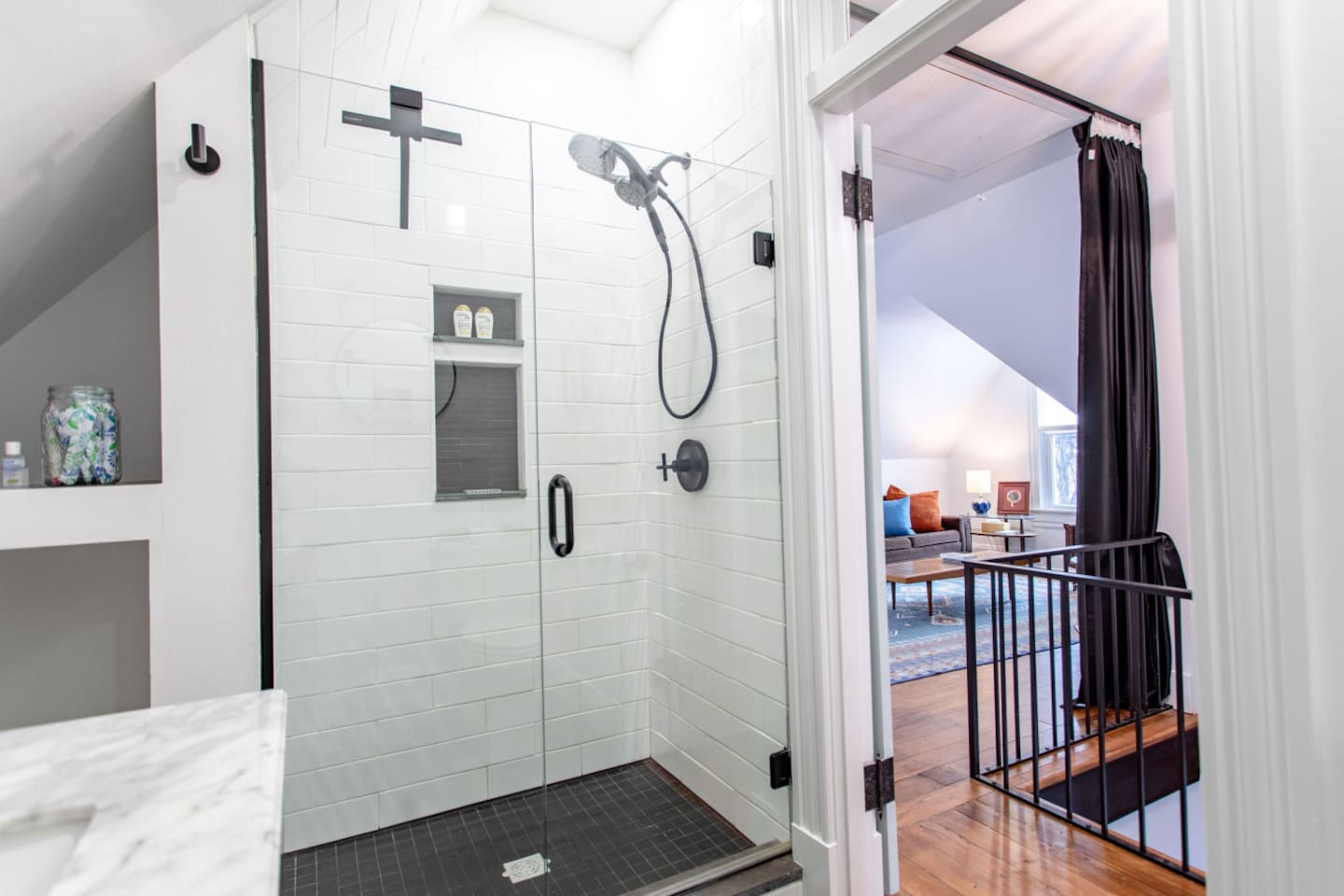 A bathroom shower with a sleek, modern design, offering a clear view of the living area beyond, creating an open and airy feel that connects the two spaces.