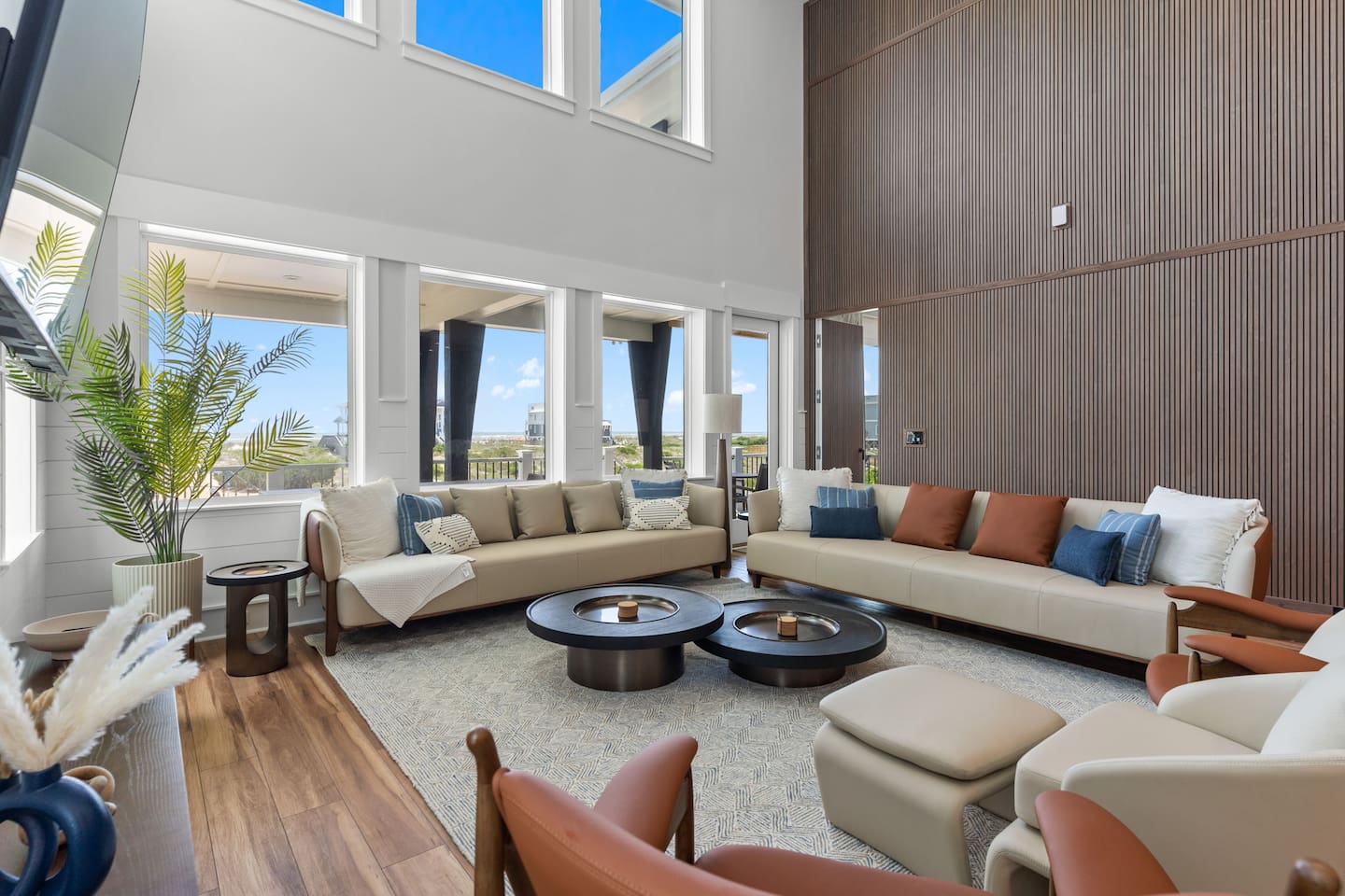 Open the door and let the ocean breeze in. With floor-to-ceiling views, a warm wood slat accent wall, and seamless access to the back deck, this space beautifully blends indoor comfort with outdoor coastal living.