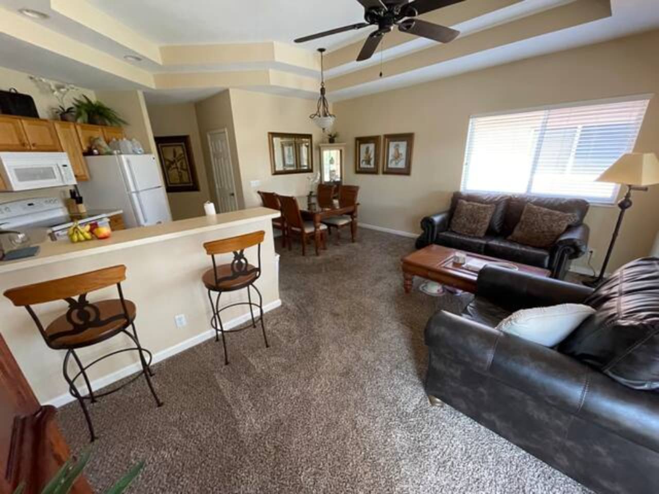 Comfortable living and dining area with cozy seating, breakfast bar seating, and large windows for natural light.