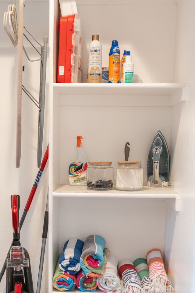 Organized laundry supplies including detergent, towels, and an iron, ensuring a smooth and efficient laundry routine.