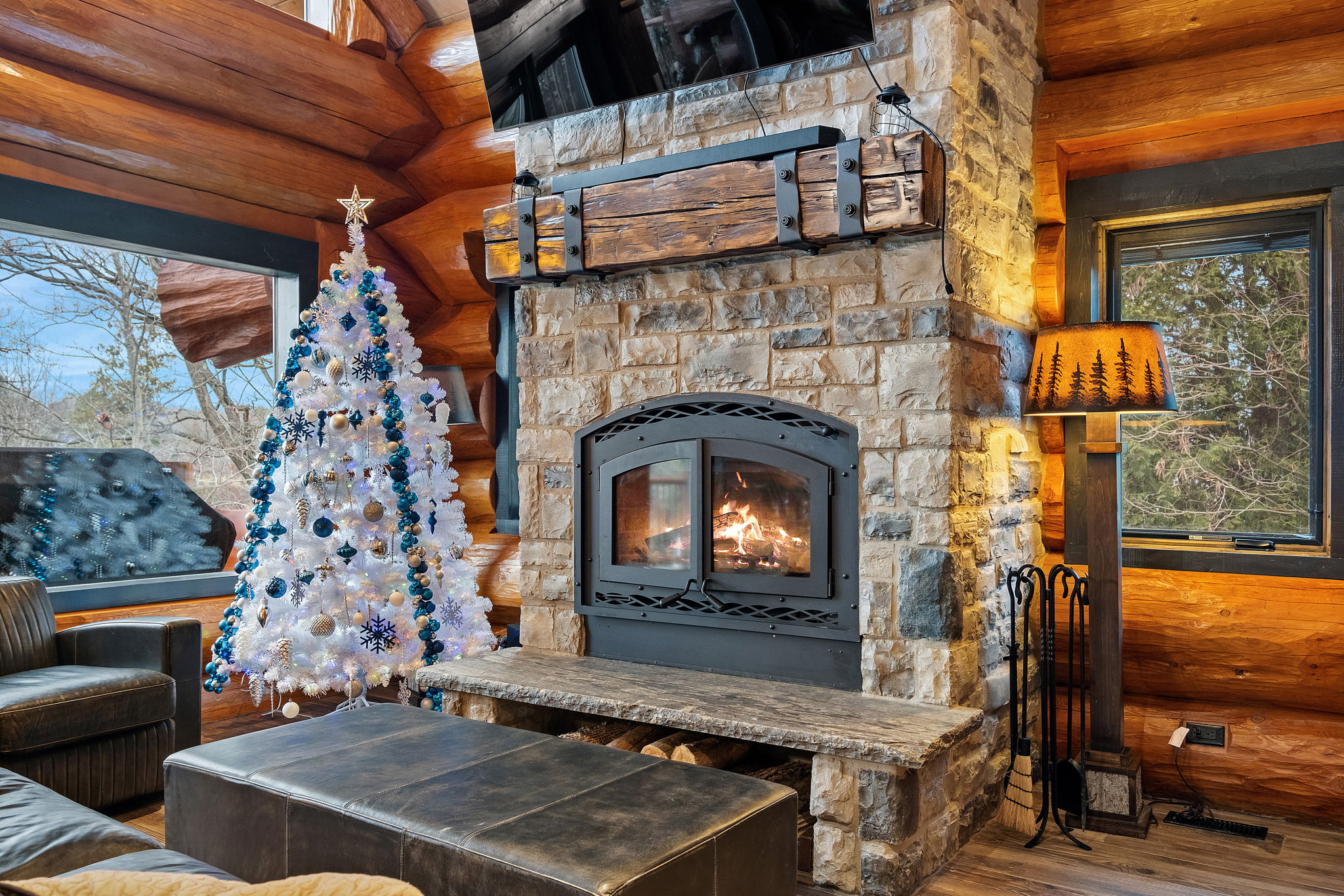 Cozy stone fireplace with a warm wood-burning fire, festive holiday décor, and inviting seating—your perfect winter escape.