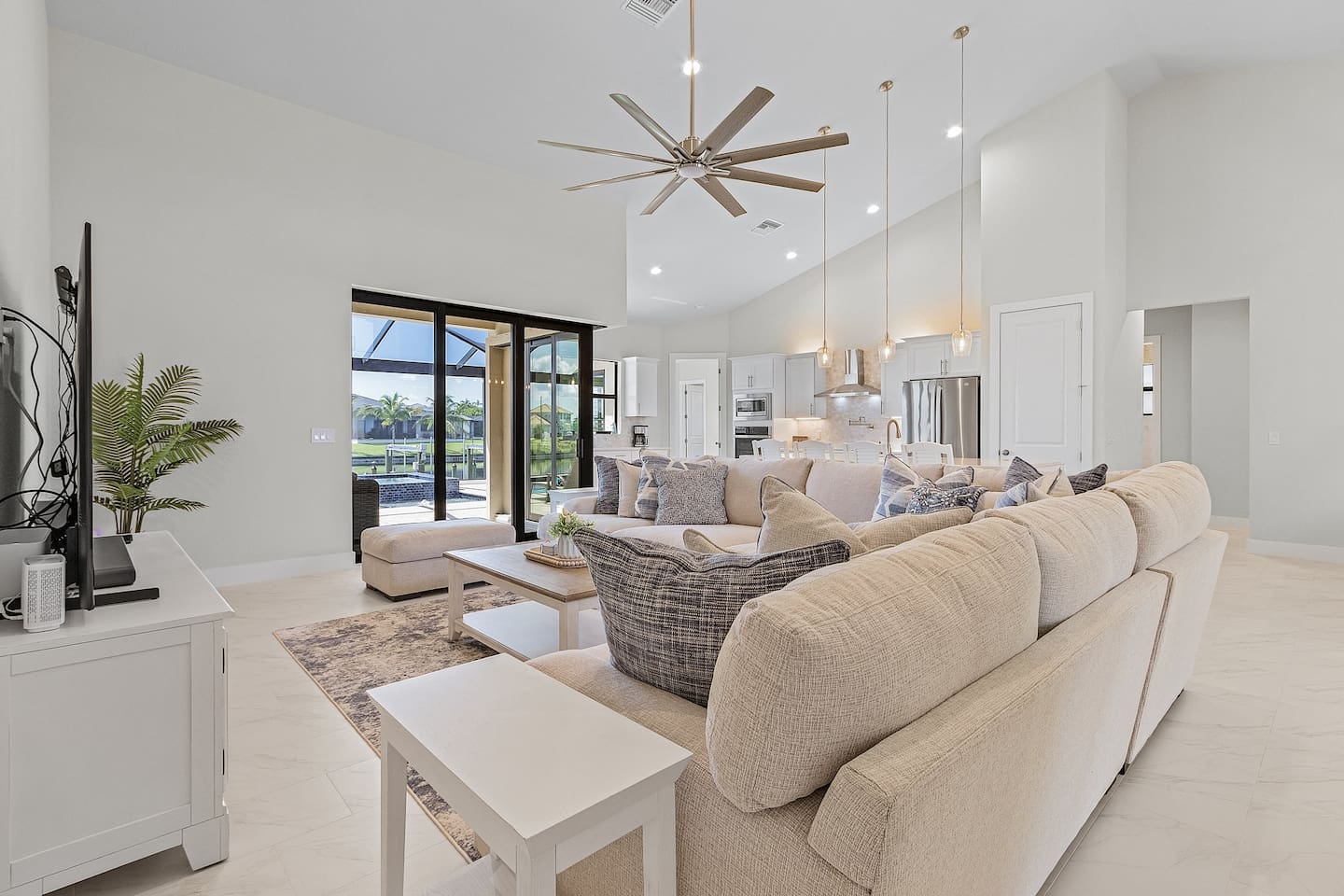 Experience the spacious coastal-designed living area featuring a large TV, easy access to the pool & spa, and stunning water views—perfect for relaxation and entertainment!