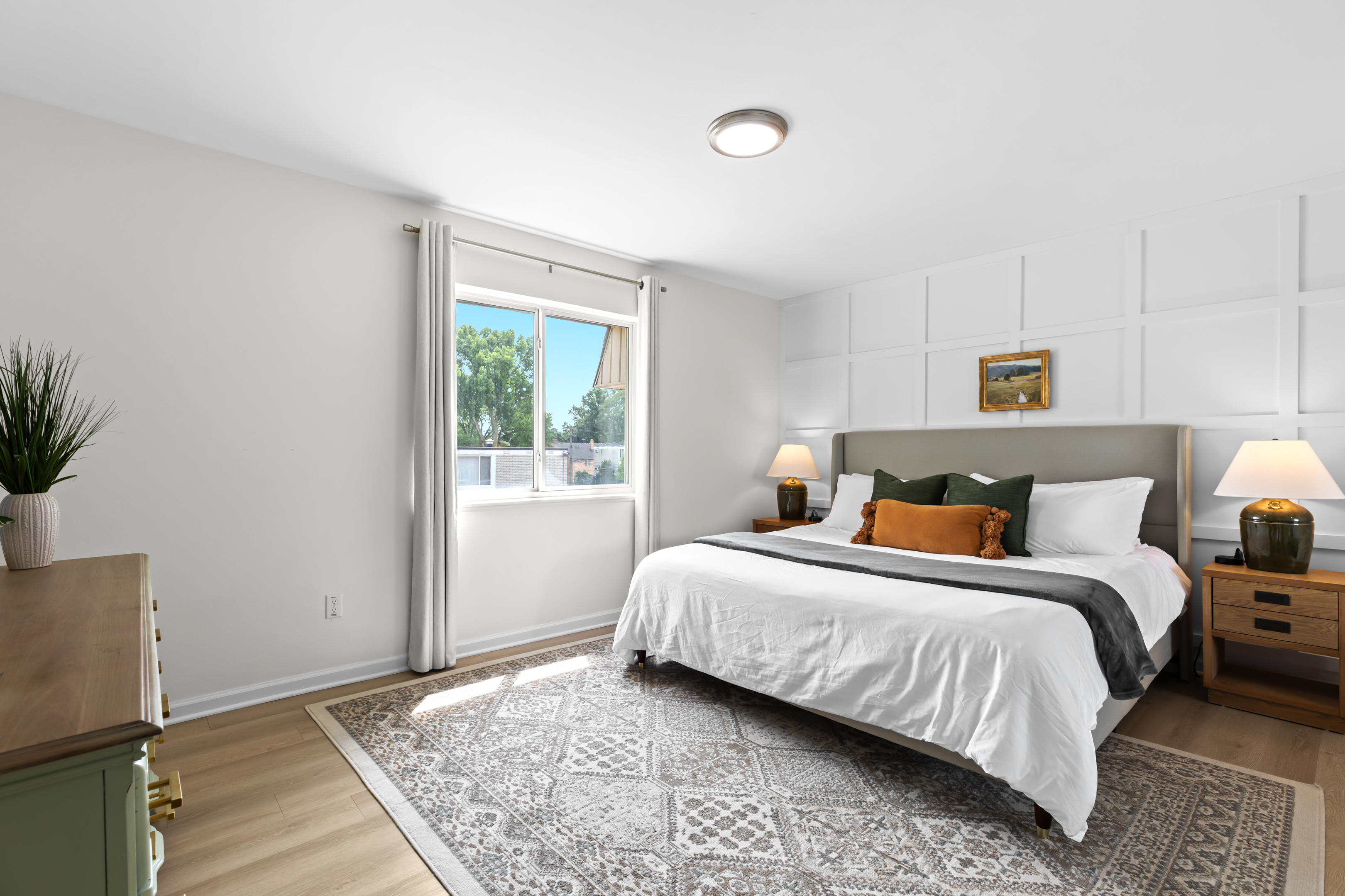 Relax in a cozy bedroom with a soft bed, neutral tones, and ample sunlight.