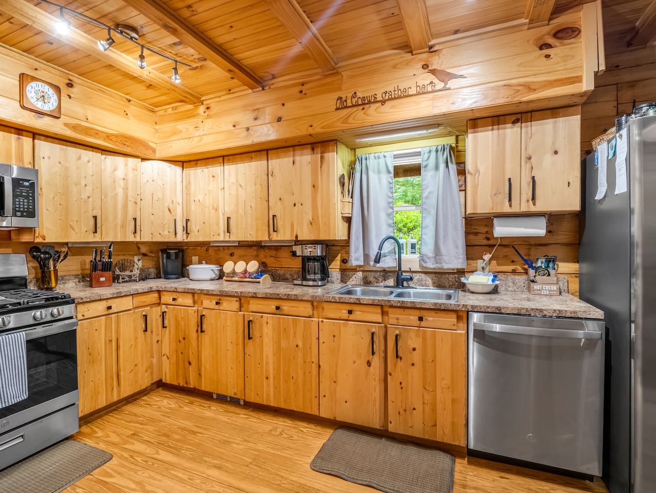 Fully equipped kitchen featuring stainless steel appliances, ample counter space, coffee area, and rustic charm