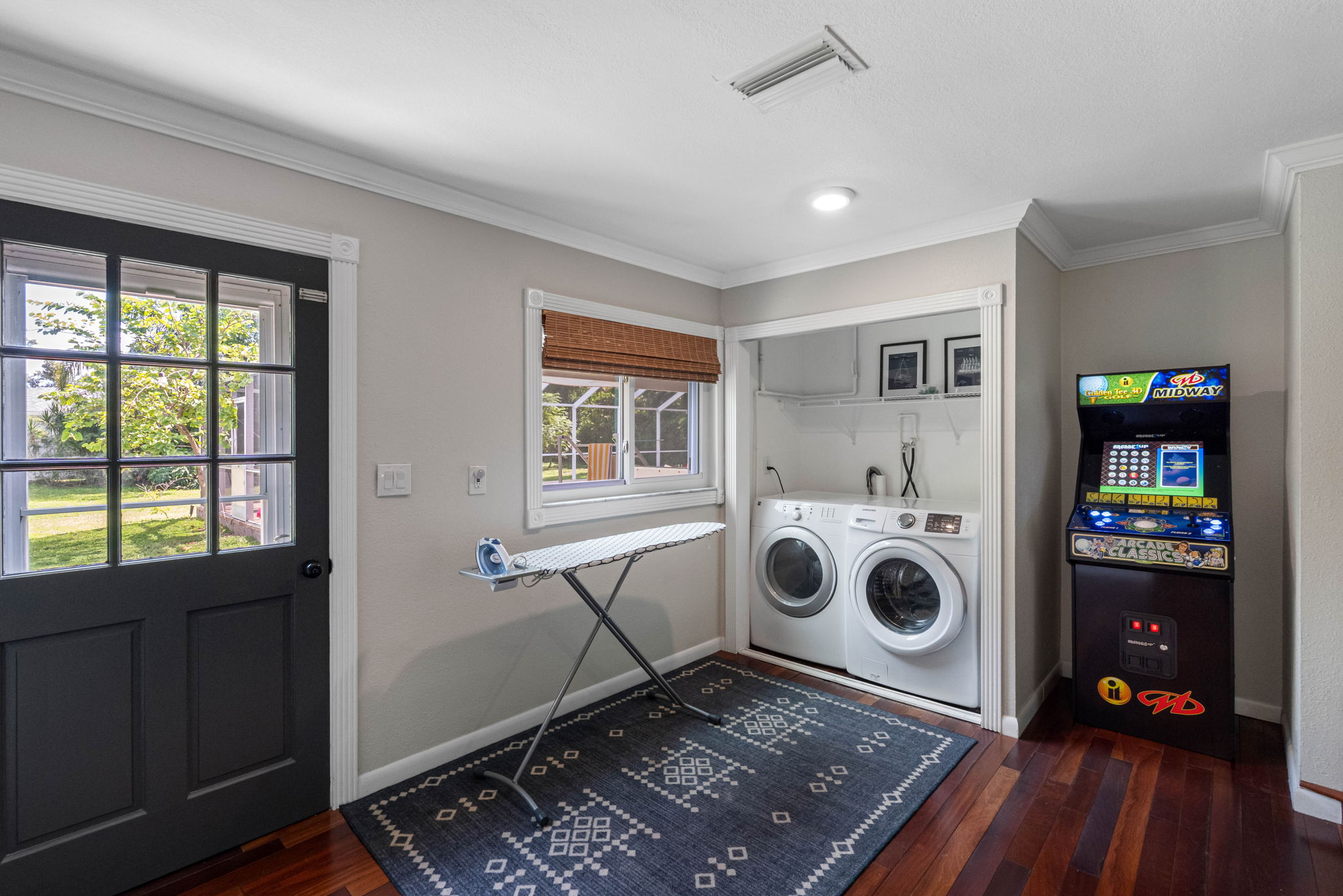 Bright laundry space with modern appliances and a nearby arcade game for added fun.