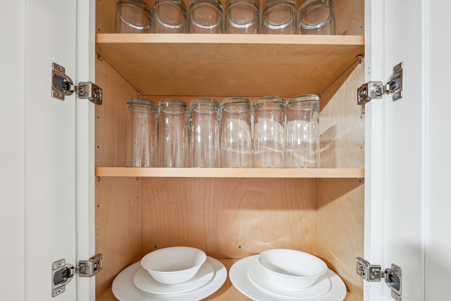 A fully equipped kitchen with a refrigerator, microwave, stove, oven,fridge, dishwasher, coffee maker, kettle, toaster, and blender. Includes plates, bowls, utensils, pots, and pans, plus four bar chairs for casual dining or socializing.
