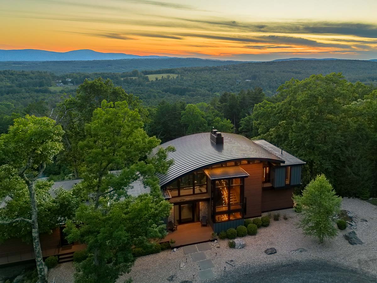 Back of Sunset Falls Estate with the sunset held in the windows &mdash; Berkshires modern mountain home