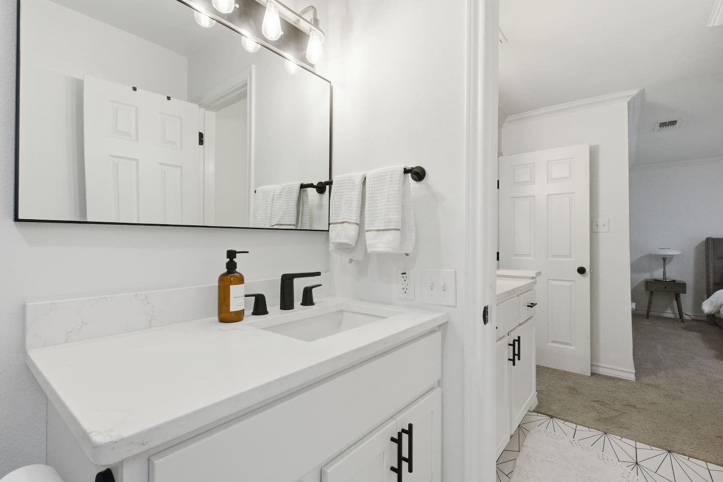 Bright vanity area with ample counter space, Ginger Lily Farms bath products, modern hardware, and clean, hotel-style presentation.