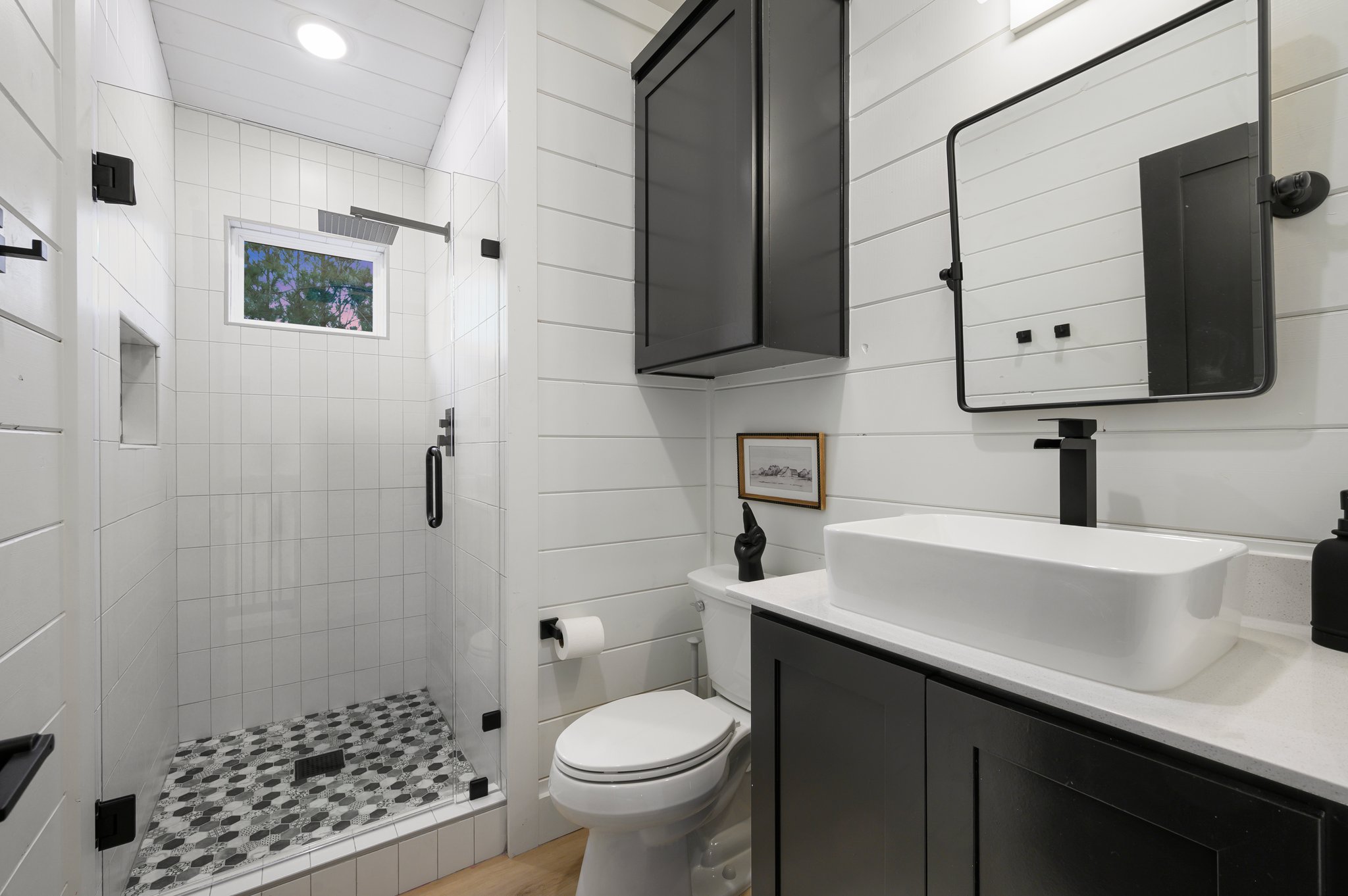 A glass walk-in shower with a rainfall showerhead adds a spa-like touch to the loft bathroom