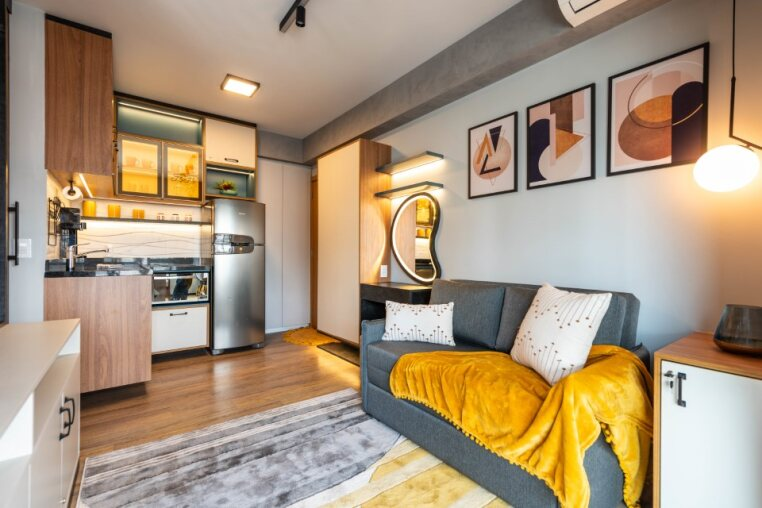 Sala integrada à cozinha equipada com geladeira, cooktop, micro-ondas, cafeteira e filtro de água — ideal para quem busca apartamento mobiliado e funcional em Pinheiros.