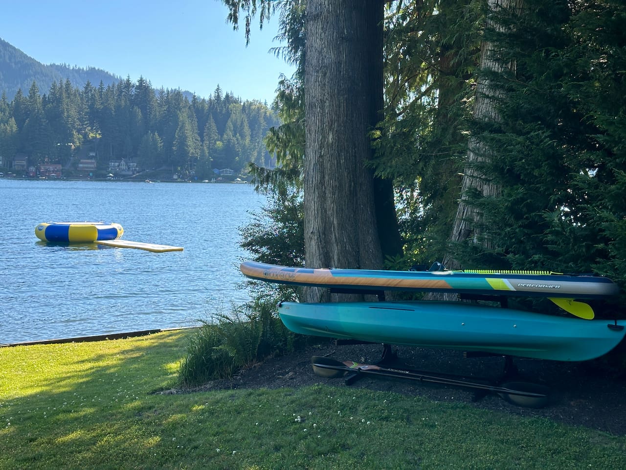 Two kayaks, two paddleboards, a water mat, and a water trampoline — all ready for fun on the lake.