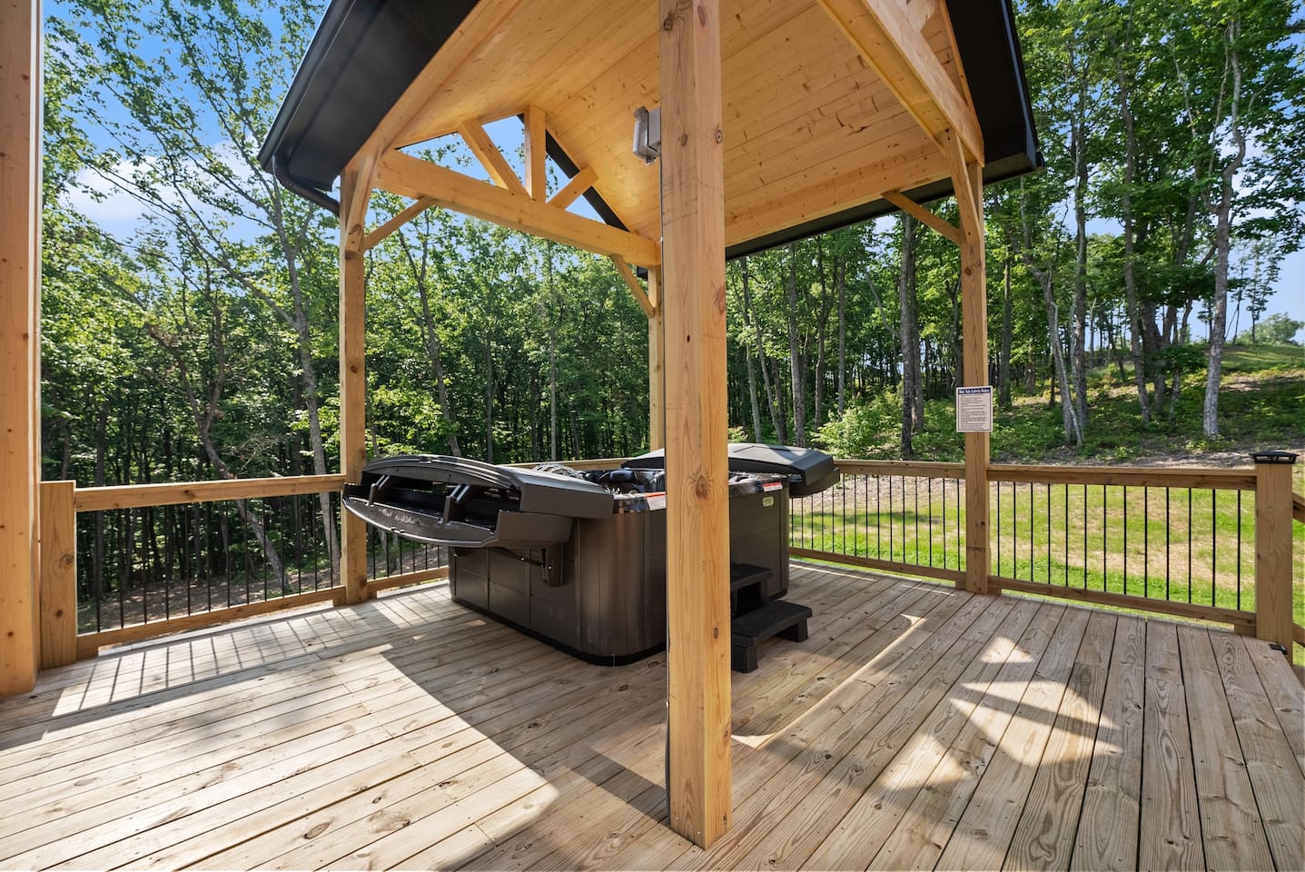 Elevated on its own deck, the hot tub offers a peaceful soak with panoramic views of the lush wooded surroundings.