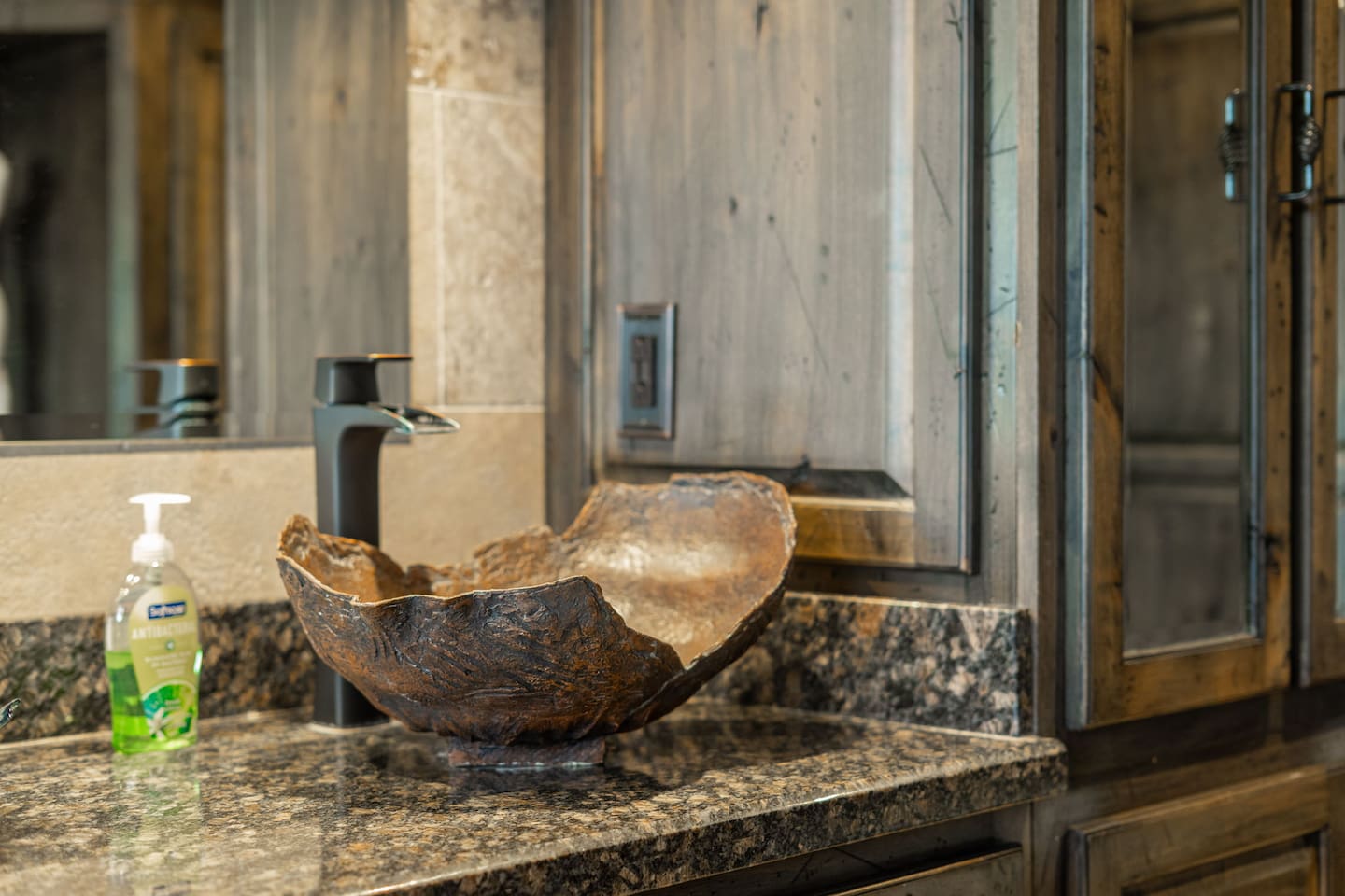 Every detail in this bathroom was chosen with intention — the organic sculptural vessel sink and distressed wood cabinetry give it a warmth and character you won't find in an ordinary rental.