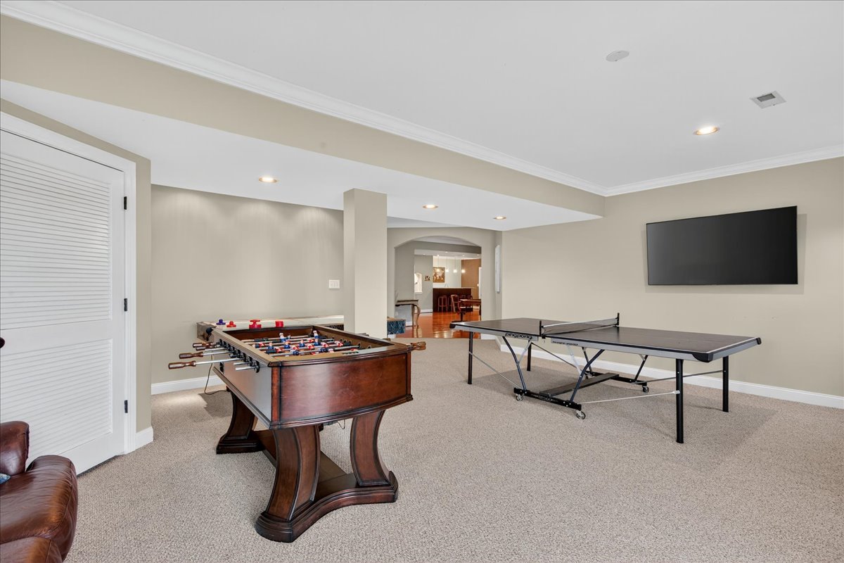 The lower level is packed with entertainment — air hockey, ping pong, foosball, plus a TV and corner couch for relaxing between games.