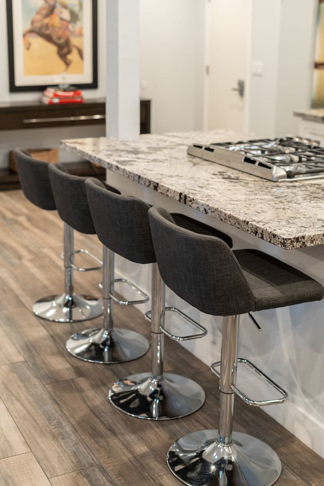 Modern kitchen countertop with a four-seater dining setup, featuring granite surfaces and sleek barstools for a stylish and functional dining experience.