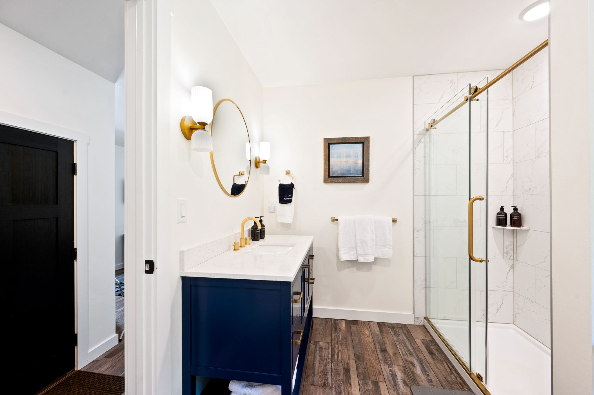 Get ready in style in this designer en suite bathroom, featuring a striking blue vanity, brushed-gold hardware, and a spacious walk-in shower.