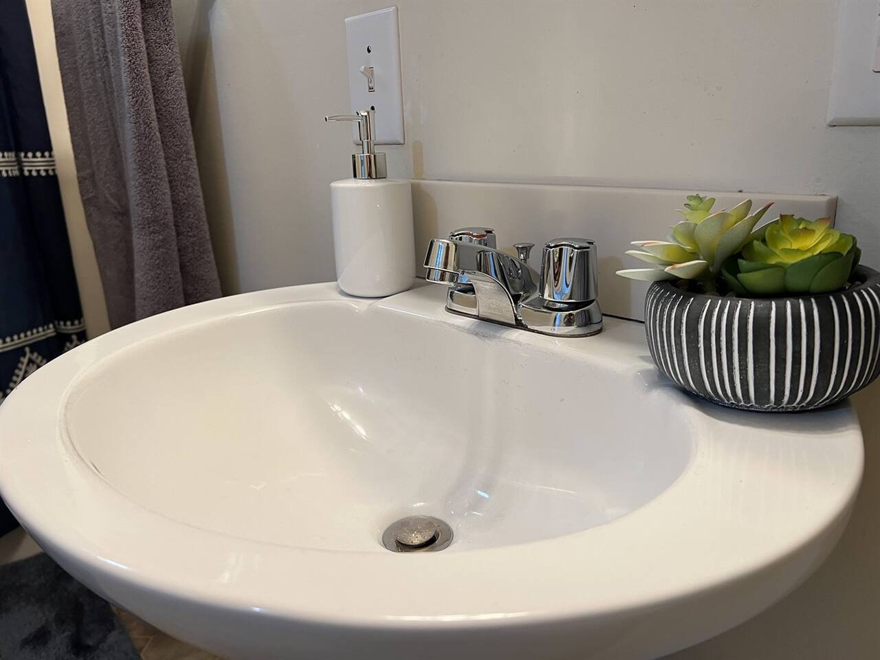 Modern full bathroom featuring a sleek sink with a stylish faucet and tasteful decorations—designed to offer a clean, functional space with a touch of elegance and contemporary charm