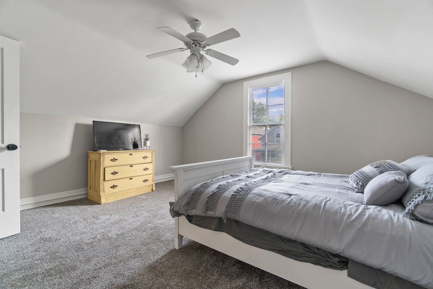 Comfortable queen-sized bed with TV for entertainment, complemented by a large window that fills the room with natural light and offers a peaceful view.
