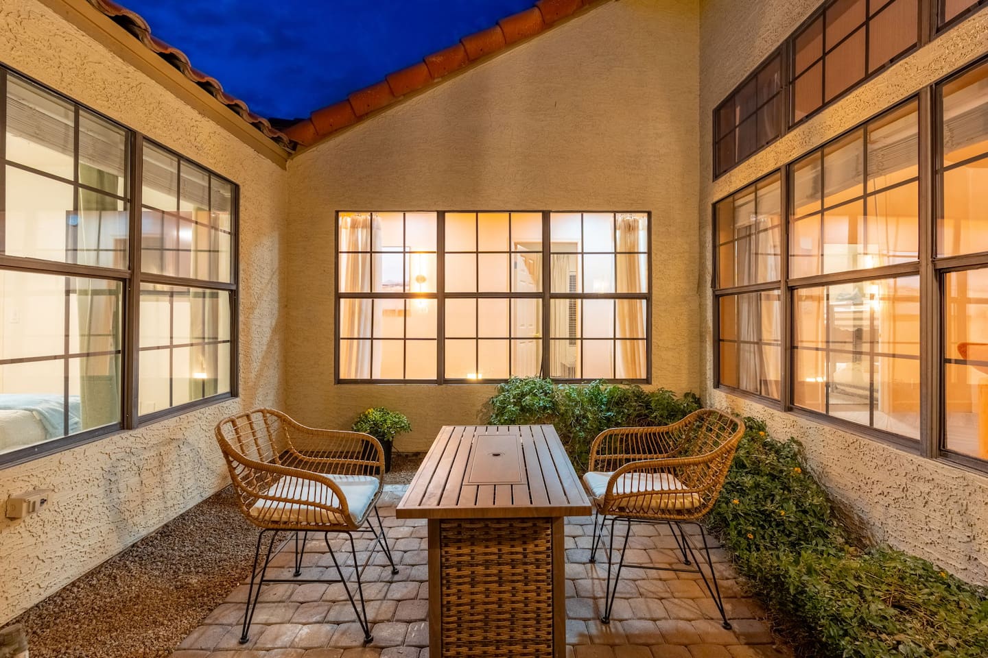 Intimate courtyard with rattan seating, wooden table, and floor-to-ceiling windows—a peaceful retreat for morning coffee or evening conversation.