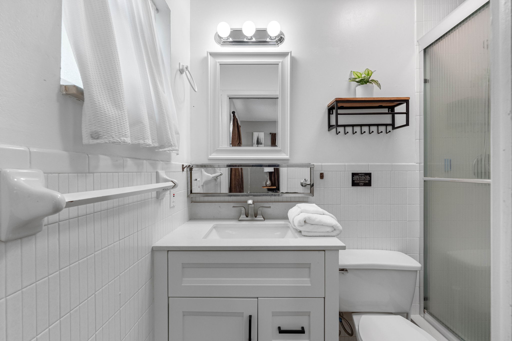 This bathroom features crisp white finishes, a sleek vanity, and bright lighting, creating a fresh and modern feel.