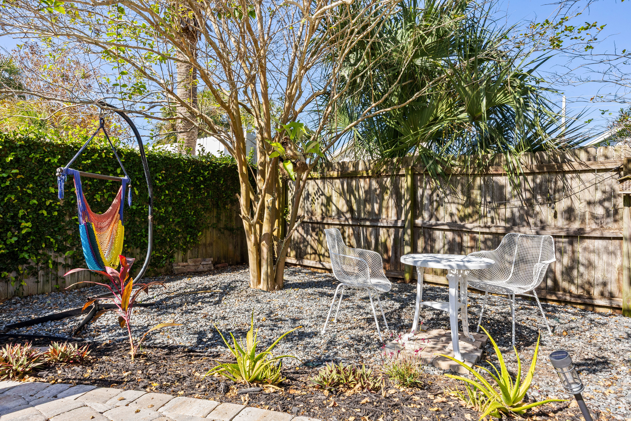 Garden Patio with Hammock and Bistro Set
A versatile outdoor space featuring a colorful hammock chair, a bistro table set, and lush tropical landscaping. A bright, inviting area designed for relaxation and conversation.
