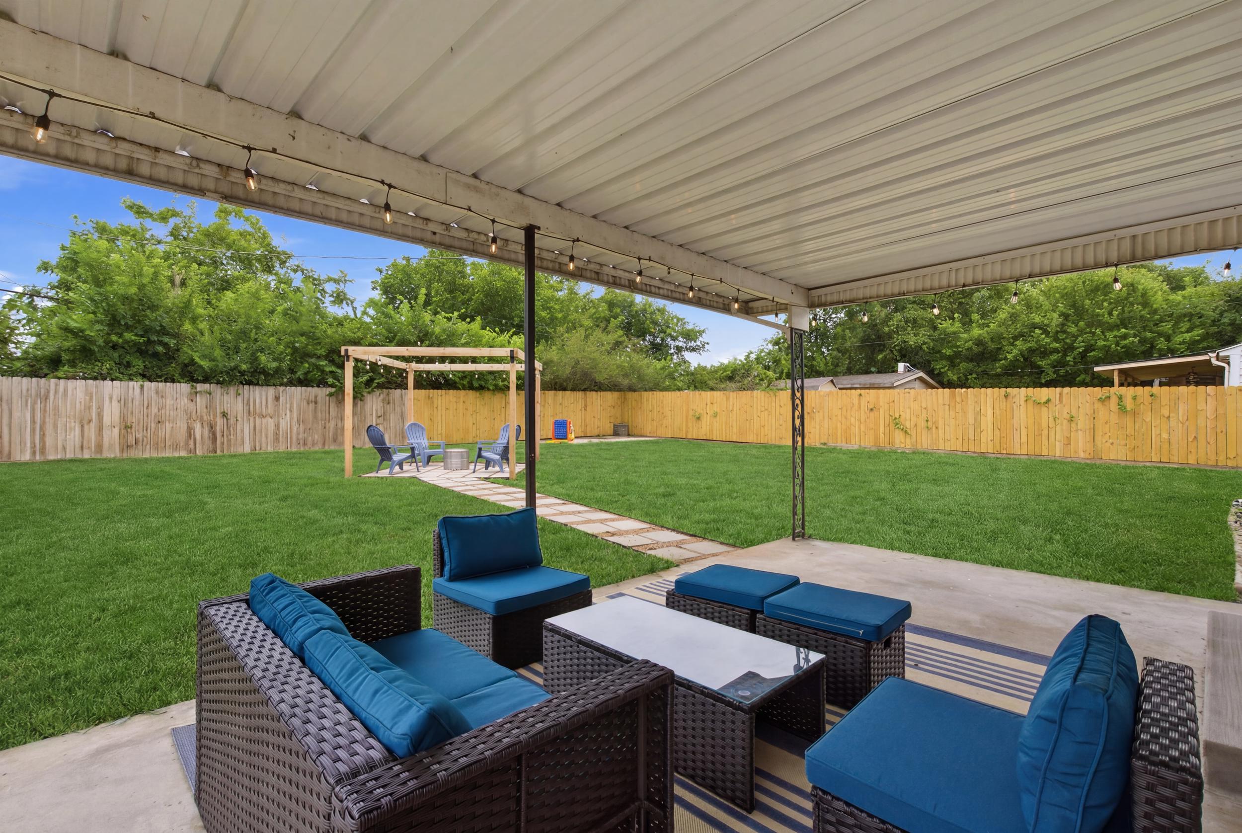Covered Patio with Outdoor Furniture overlooking the Fire Pit, Pergola, and Lifesize Outdoor Games. Easy indoor-outdoor flow for group hangouts.


