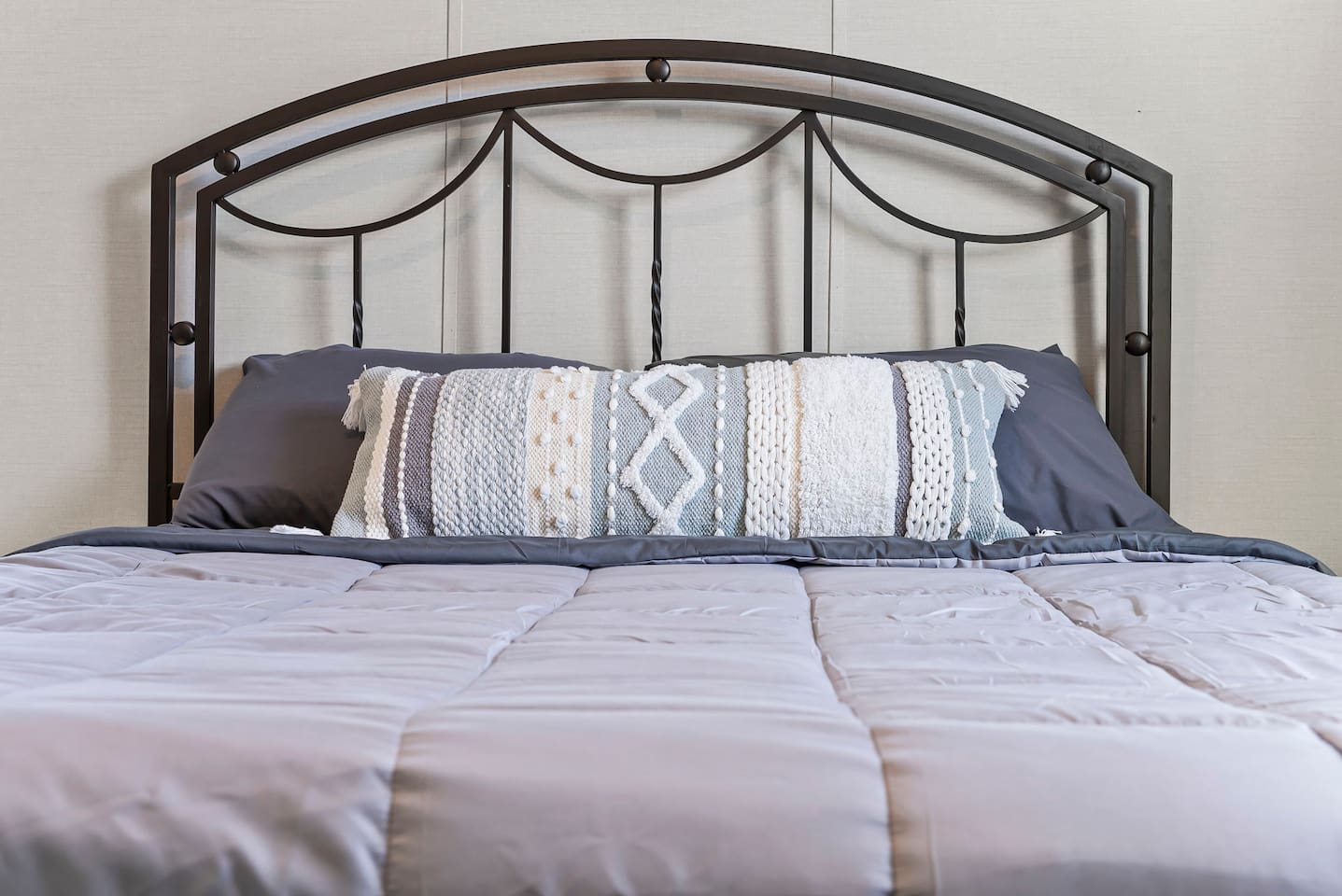Detailed view of the stylish headboard and layered pillows, adding a warm and inviting touch.