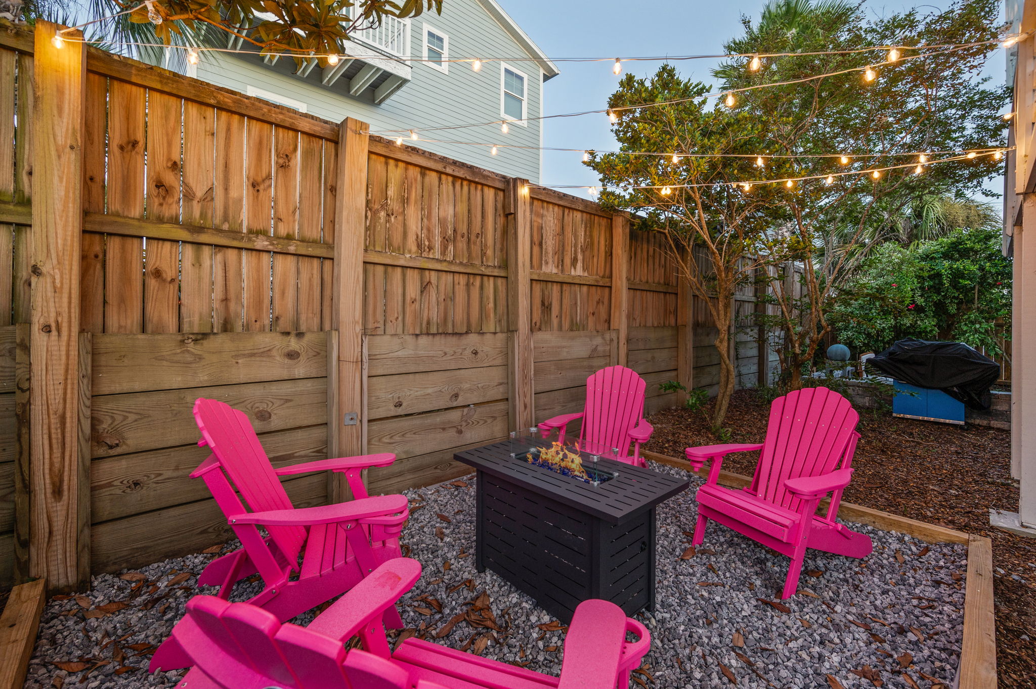 This photo features four sturdy pink outdoor chairs with built-in cup holders, arranged around a propane fire feature. We provide the propane, so you can just sit back, relax, and enjoy a cozy fire under the stars!
