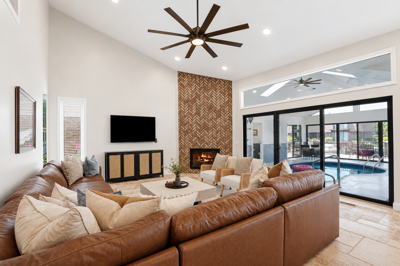 Gather in this spacious open-concept living room featuring a cozy sectional, modern fireplace, soaring ceilings, and seamless indoor-outdoor flow perfect for relaxing and entertaining.