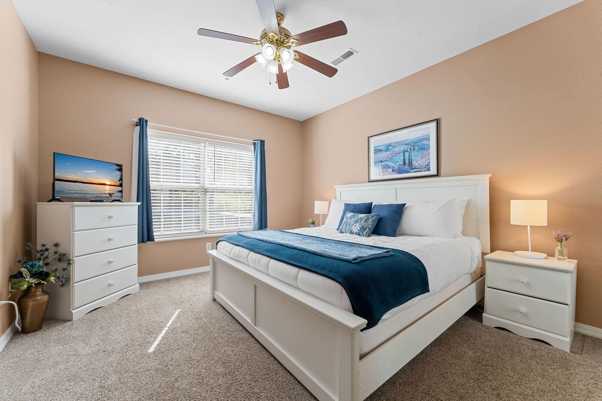 The second bedroom is spacious and has a king bed, dresser and smart tv