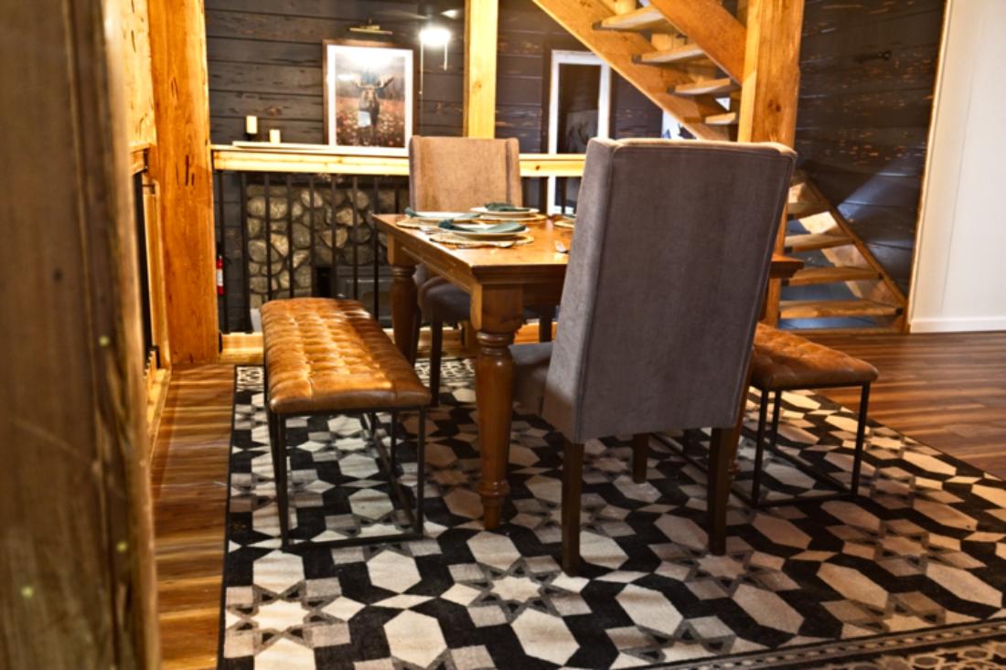 Share meals and memories at your warm wood dining table, with plush seating, leather benches, and a view of the rustic stone fireplace just steps away from the loft staircase.