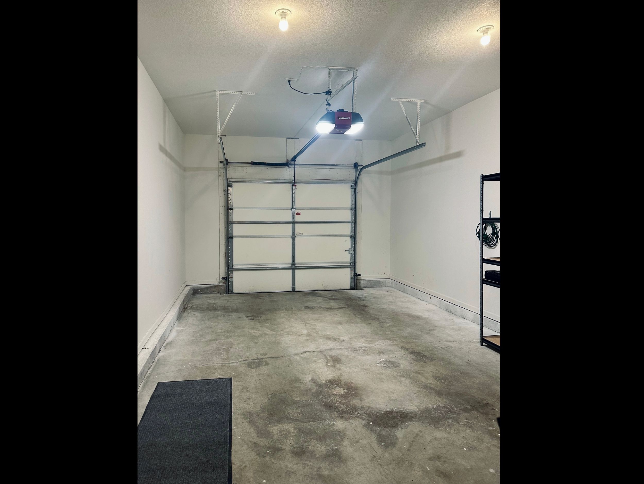 Standard one-car garage offering secure covered parking with additional side space for practical storage and shelving.