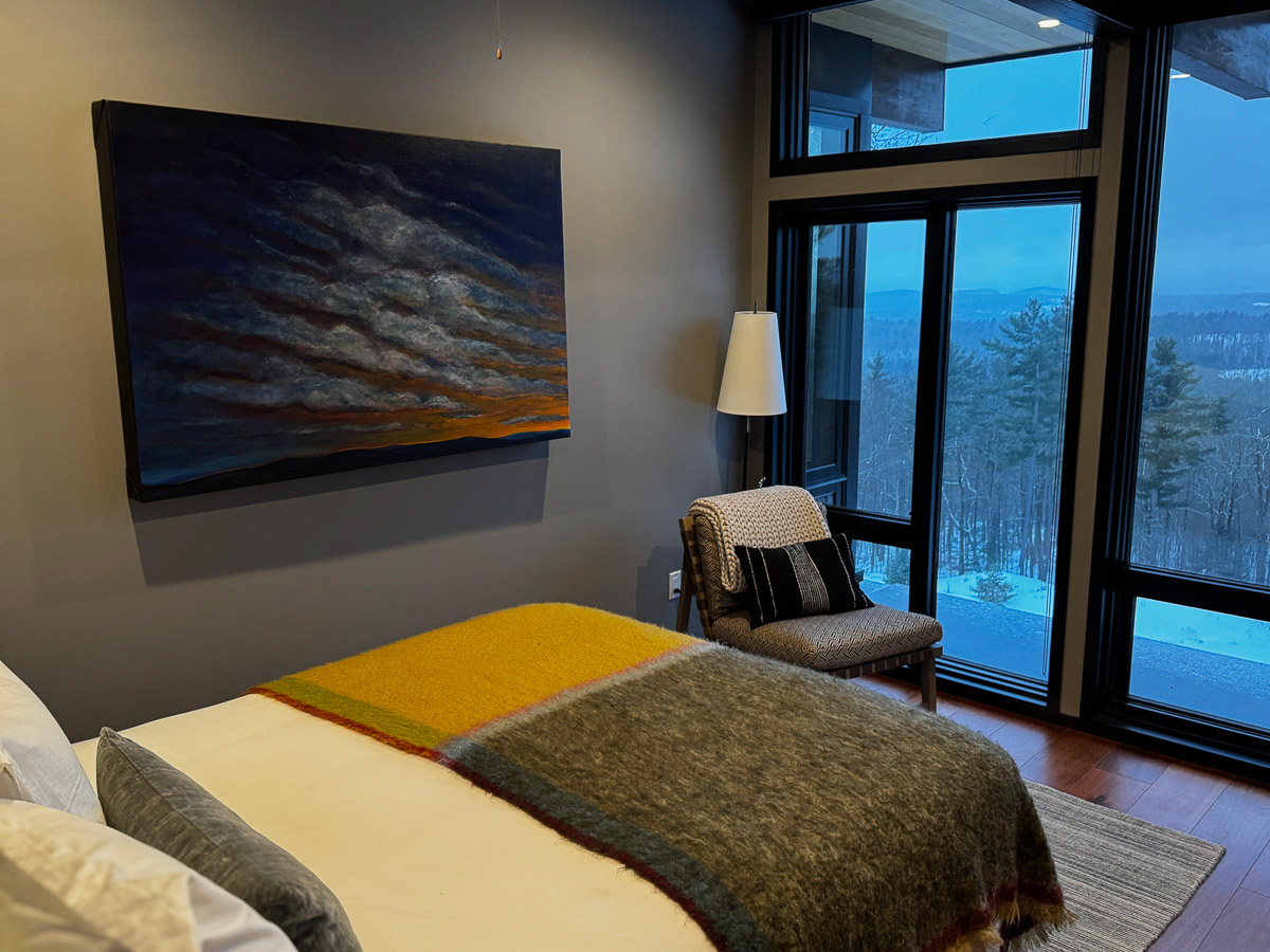 Bedroom One at Sunset Falls &mdash; evening valley view through corner glass, cloud painting above the bed