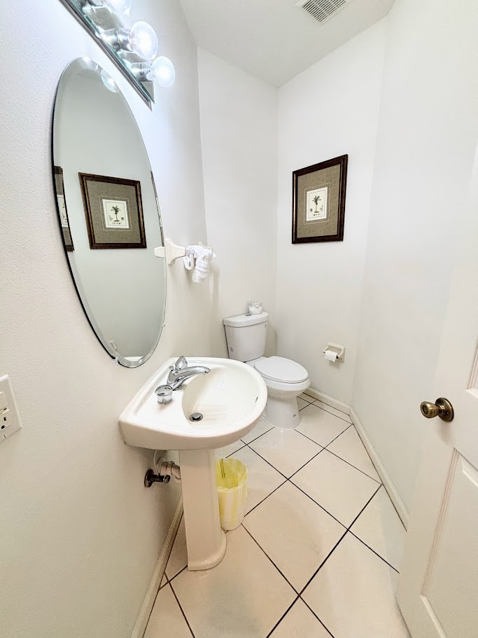 Convenient half bathroom with pedestal sink, tile flooring, and clean neutral finishes.