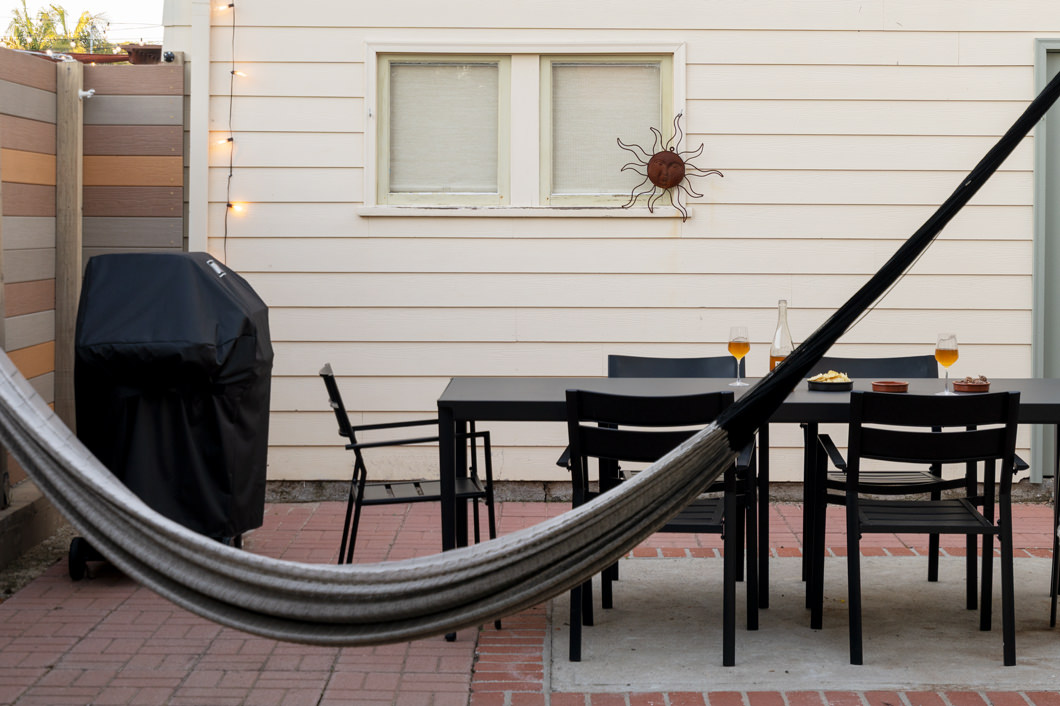 The patio includes a hammock, dining table, and Weber gas grill.