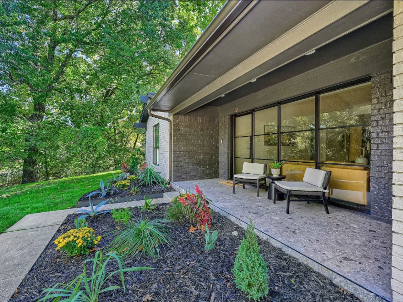 Covered front porch with seating, landscaped garden beds, and direct access to the home’s main living spaces.
