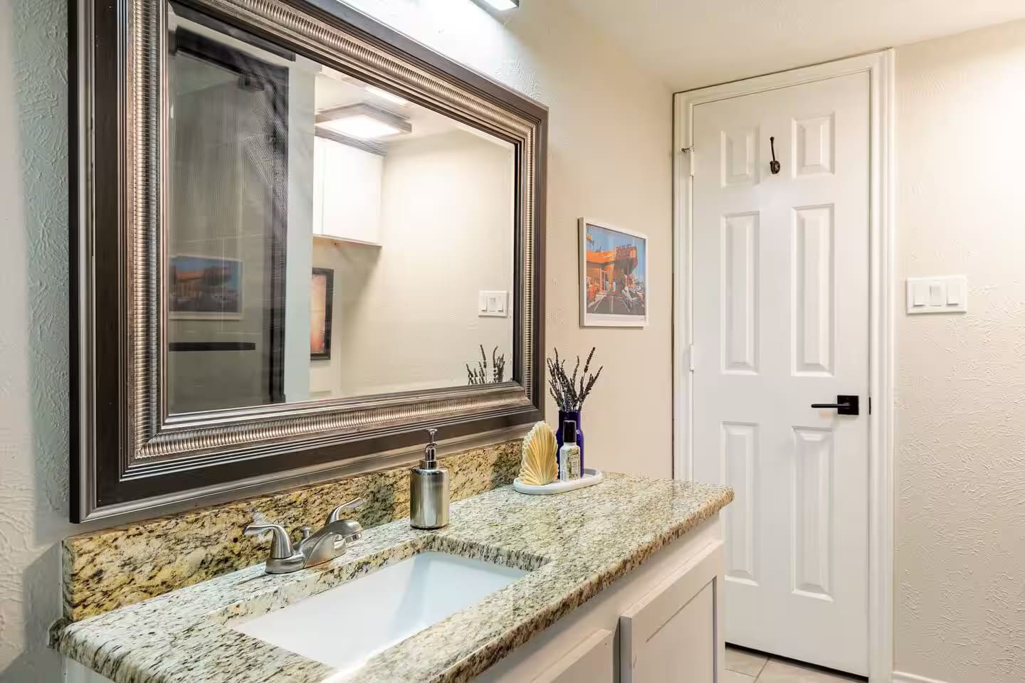 Bathroom with wide vanity, granite countertop, and large mirror.