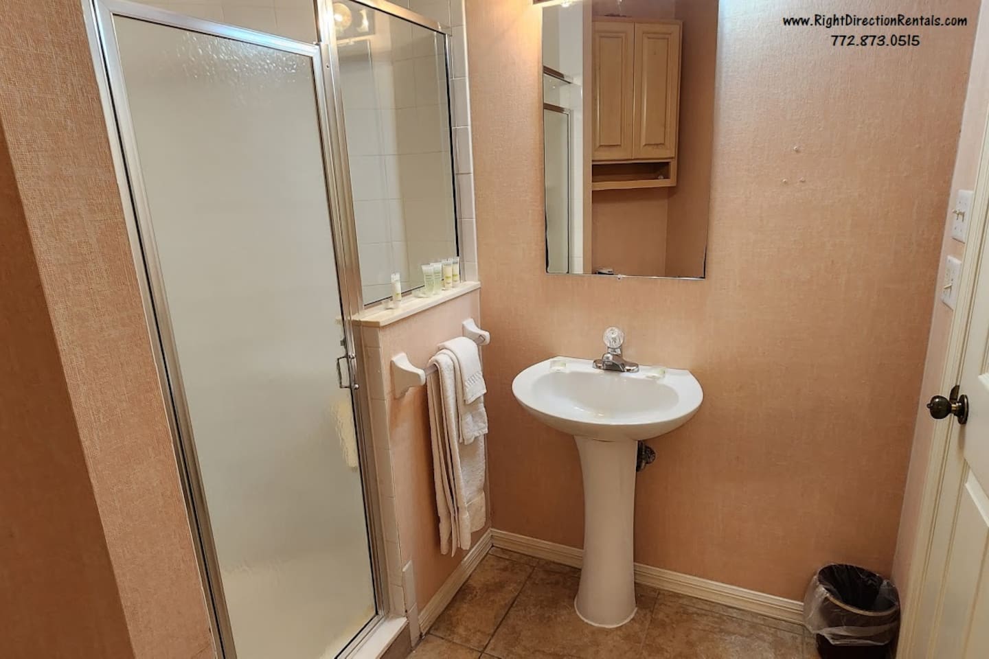 Bathroom featuring a pedestal sink, shower enclosure, tile flooring, and clean neutral finishes.