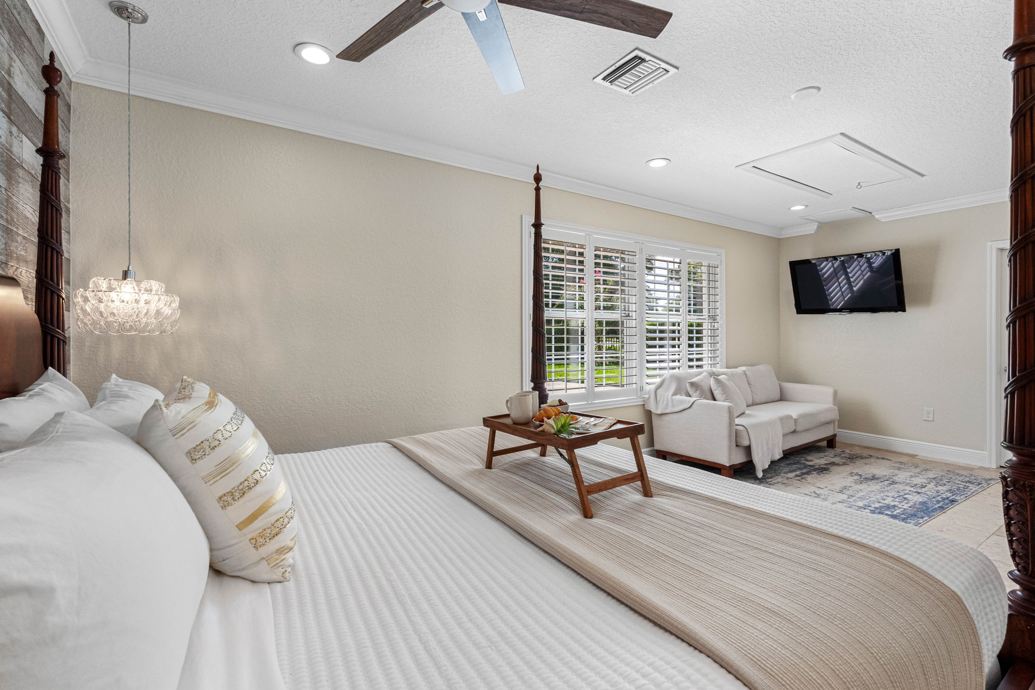 Elegant and serene, this bedroom combines a classic wooden bed frame with a cozy seating area, perfect for unwinding with a book or TV.