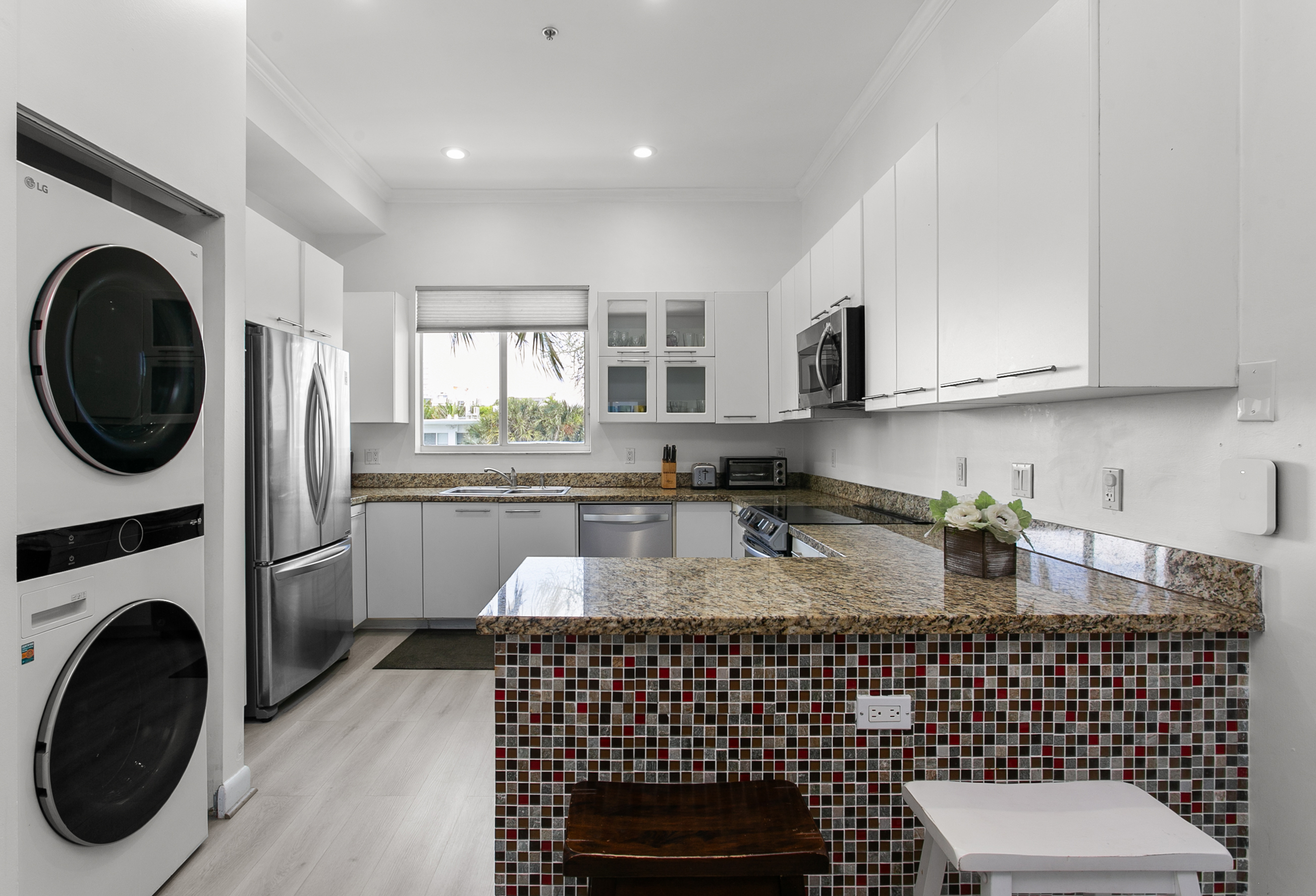 Induction range, French door fridge with bottom freezer, and breakfast counter. LG laundry tower right next to it.