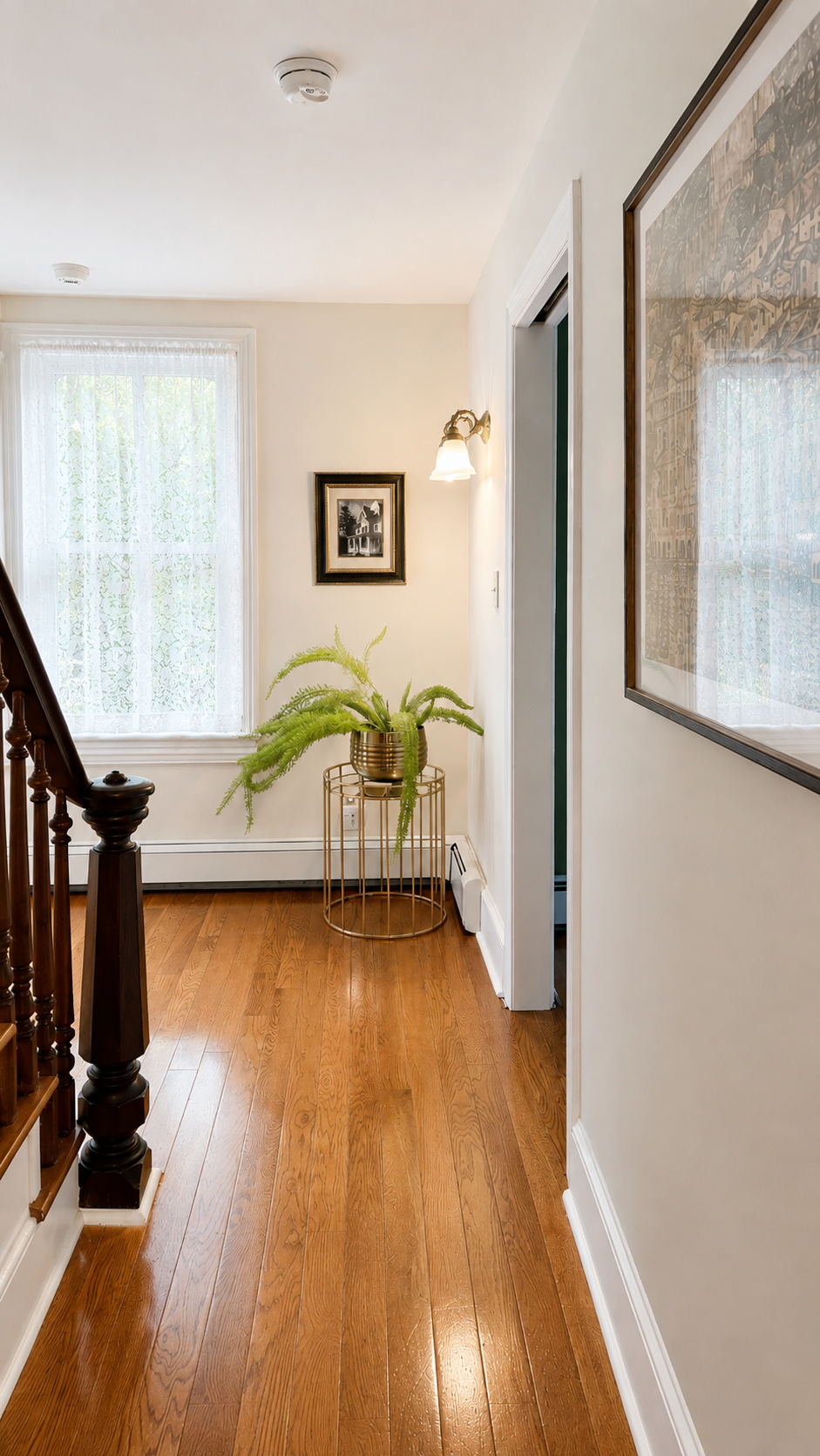 The second floor landing — original hardwood floors, walnut staircase, and a framed photo of the cottage as it looked in 1974. Some things haven’t changed a bit.