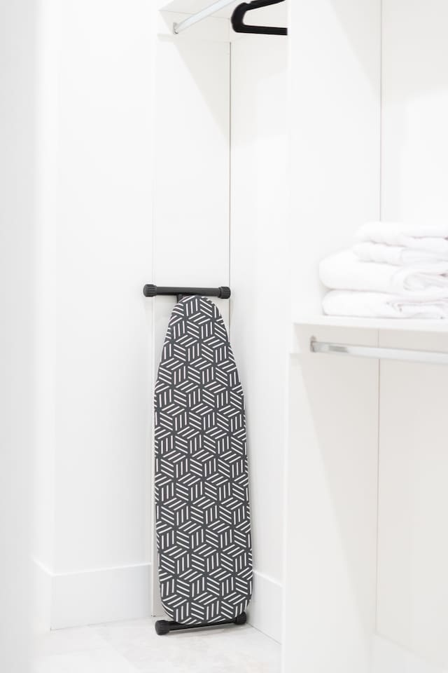 Closet space featuring an ironing board and neatly folded fresh linens.