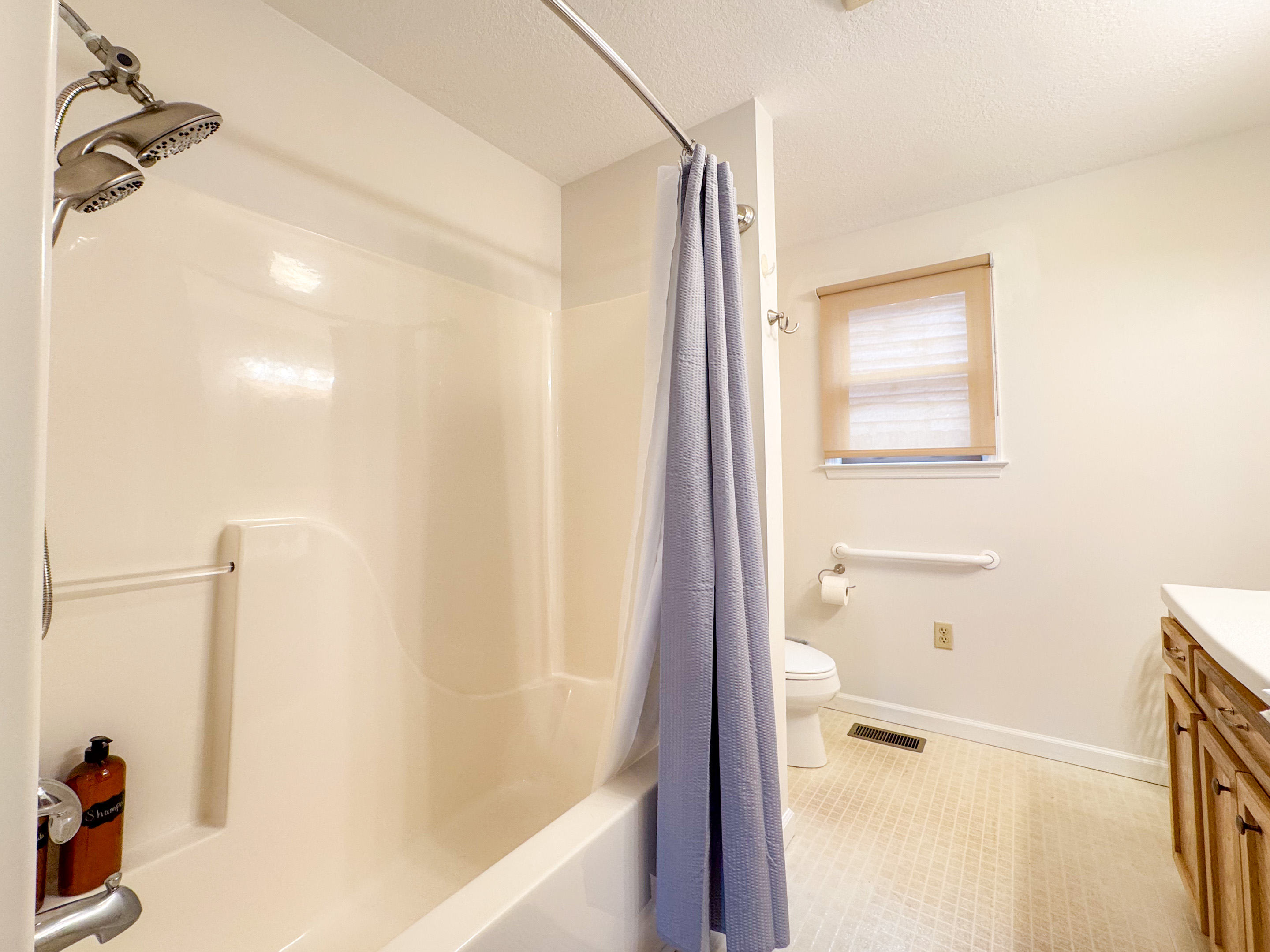 The ensuite bathroom features a tub/shower combination, toilet, vanity, grab bars, and a separate stall shower with low clearance! A rare treat!