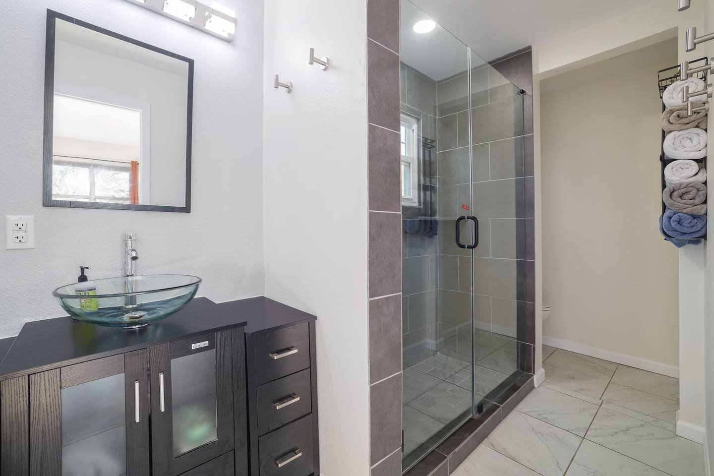 Freshen up in a sleek ensuite bathroom featuring a spacious walk-in glass shower and clean modern finishes. Thoughtfully stocked and designed for comfort, it’s the perfect reset after a day of fun and exploring.