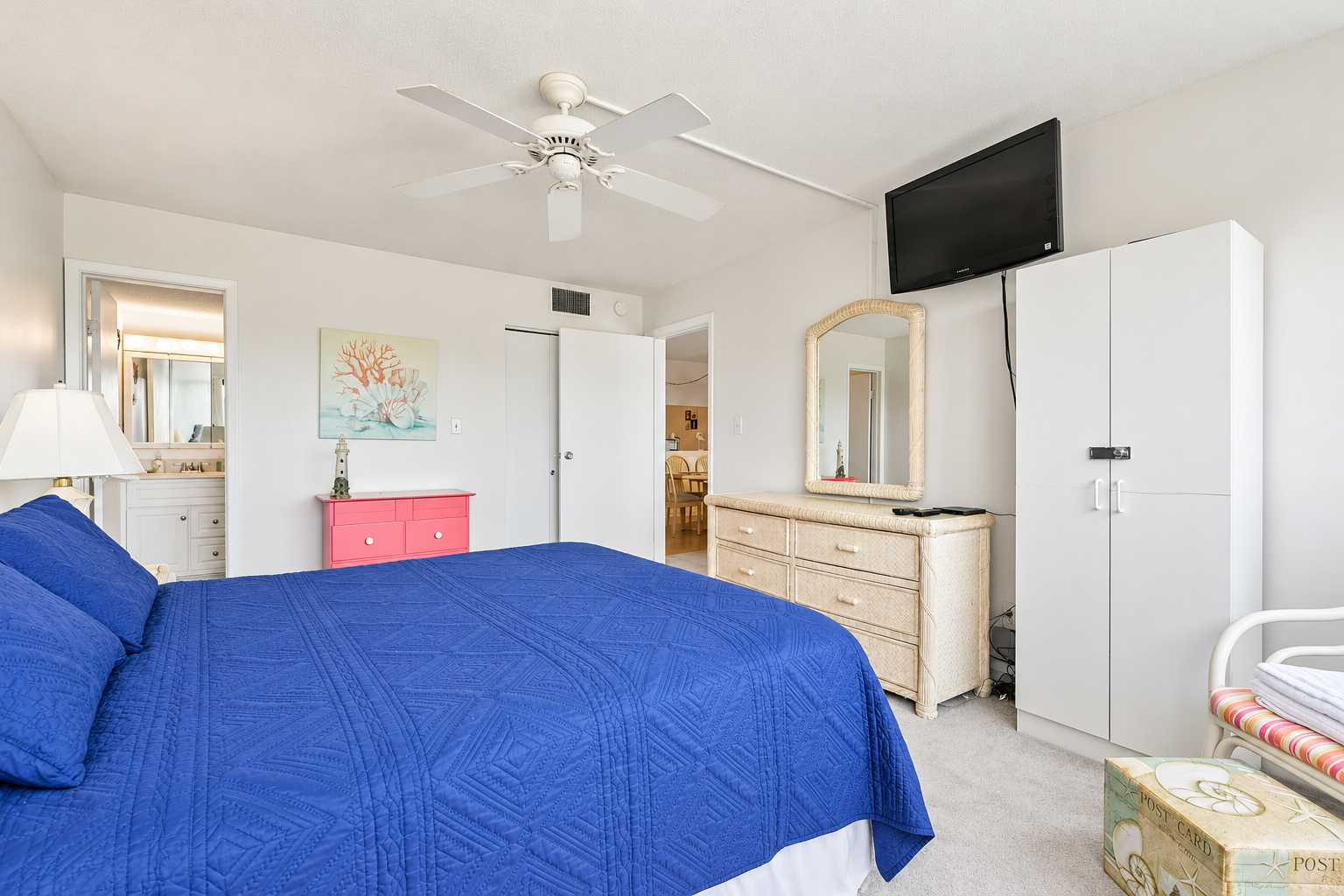 Queen bedroom with wall-mounted TV, dresser storage, and ensuite bathroom access.